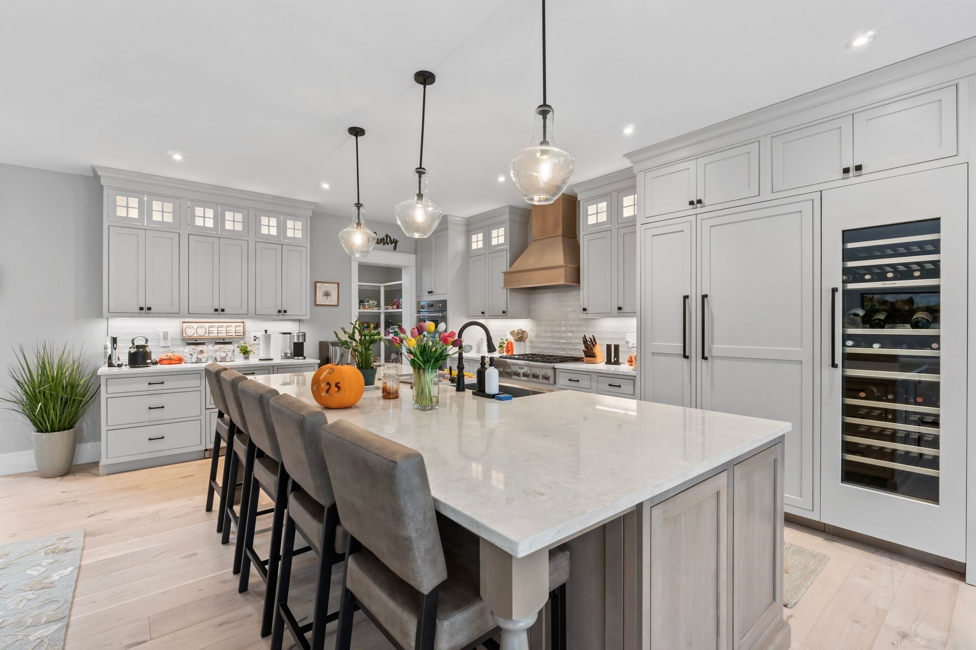 Modern kitchen with a large island, gray cabinets, pendant lights, and a built-in wine fridge