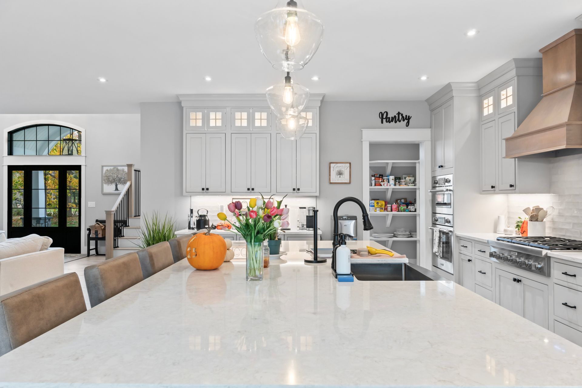 Bright modern kitchen with large island, pendant lights, gray cabinets, and a vase of flowers
