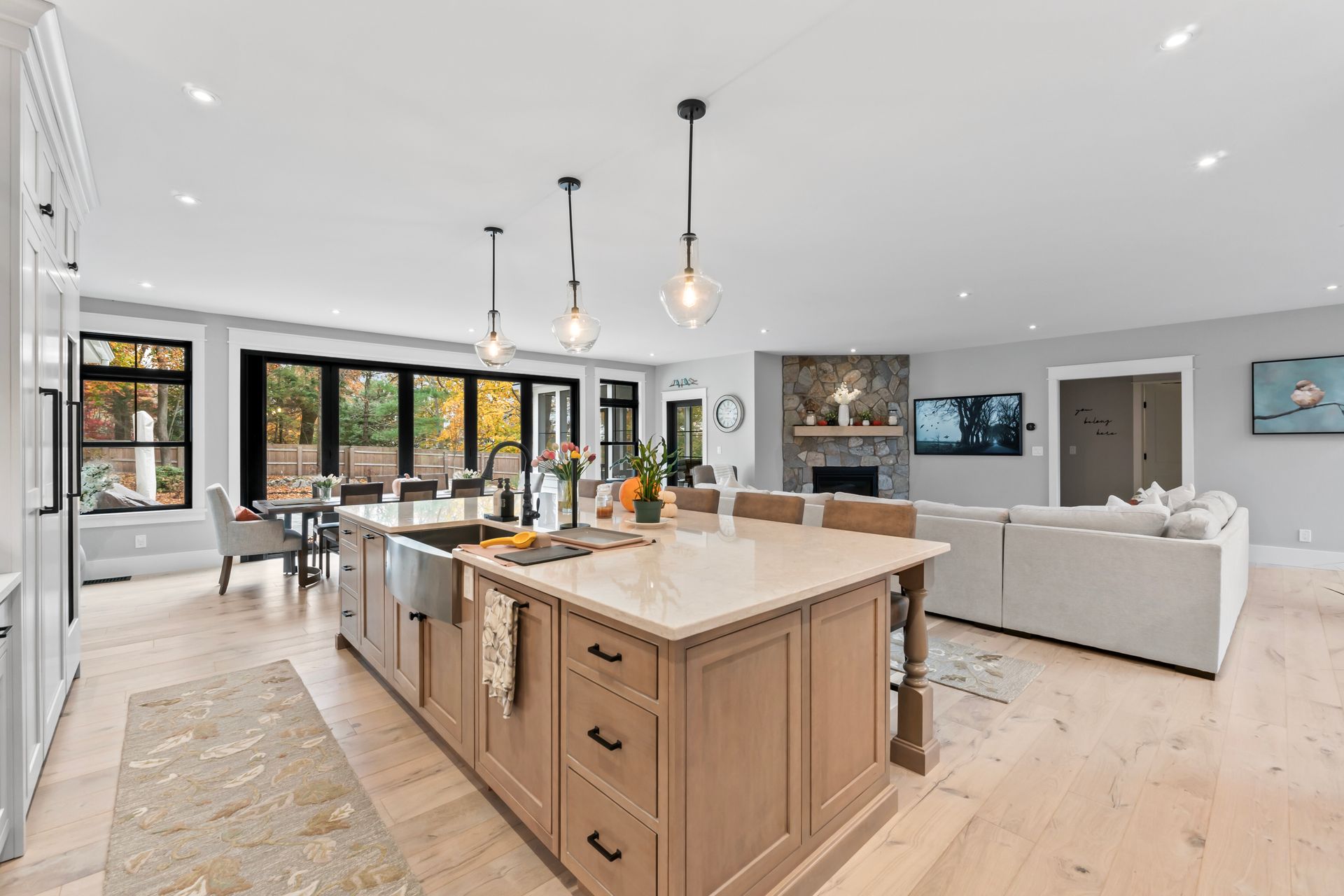 Bright, modern open-plan kitchen and living room with wood island, pendant lights, and large windows