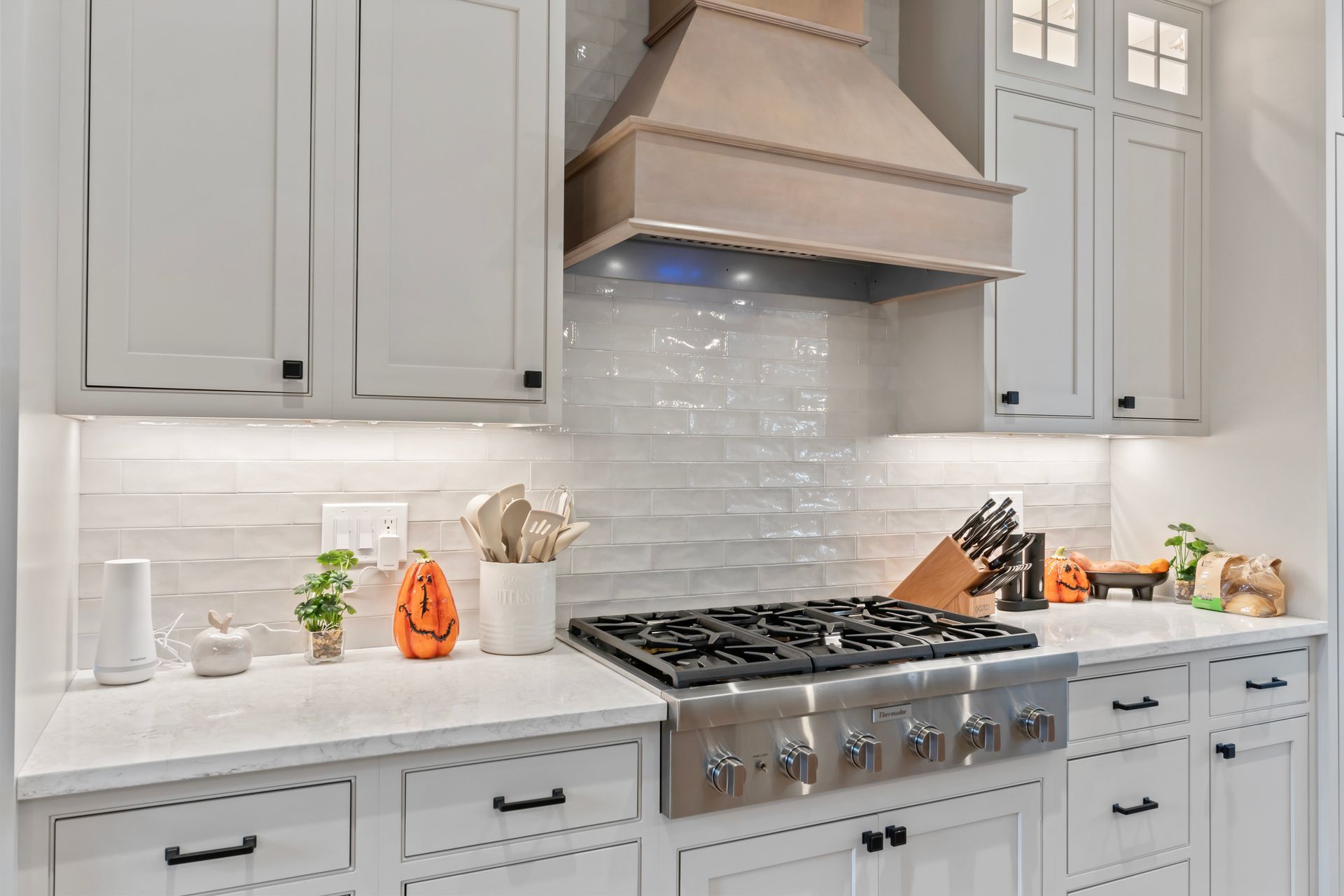 Bright white kitchen with stainless range, marble countertop, and light gray cabinets