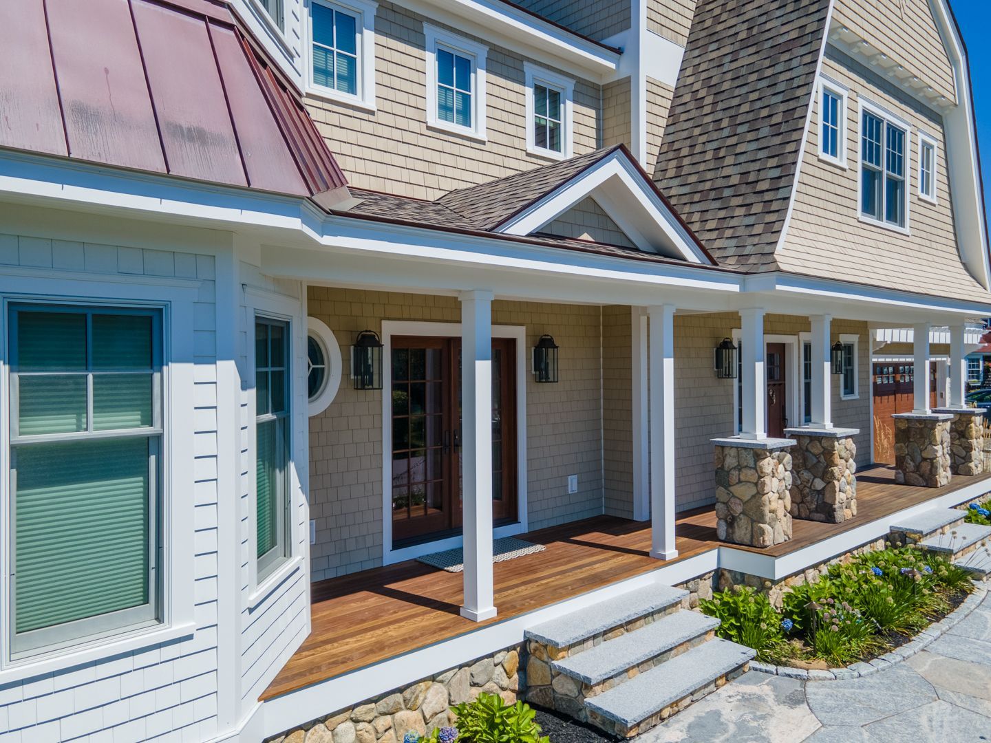 Row of townhouse porches with white trim, blue siding, wood steps, and stone columns under a clear sky