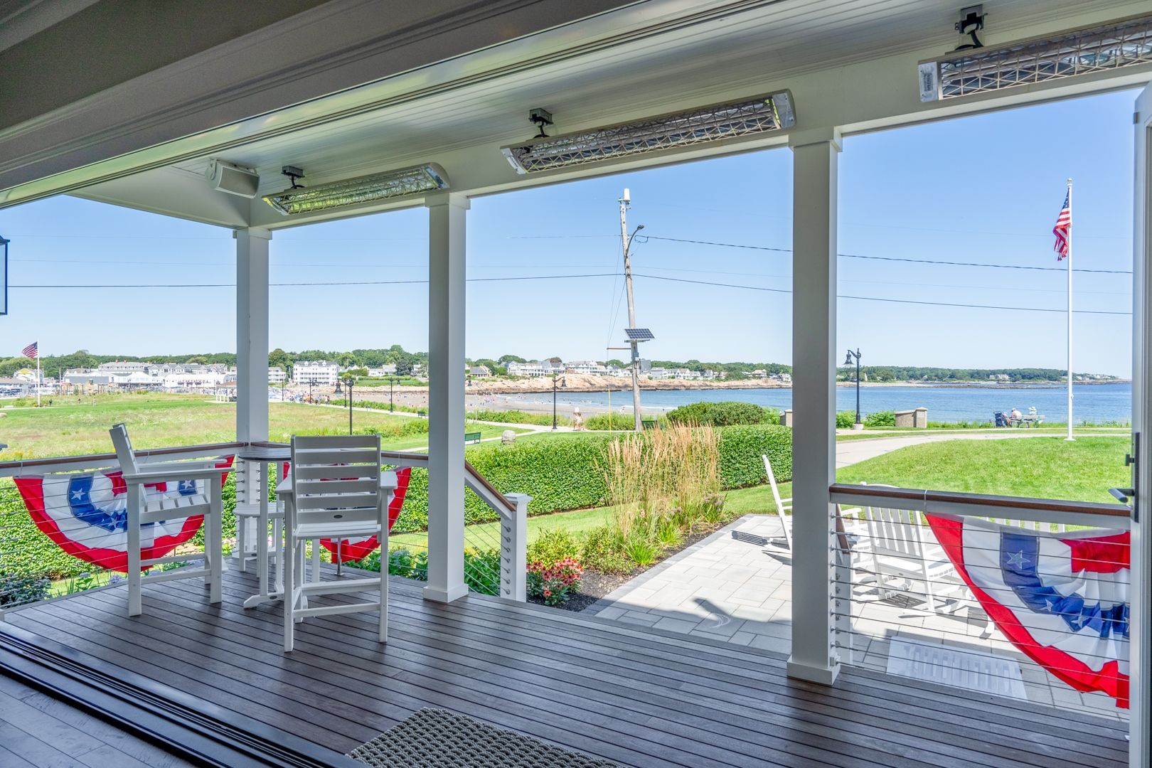 Porch overlooking a marsh and bay with patriotic bunting on the railing and chairs on the deck
