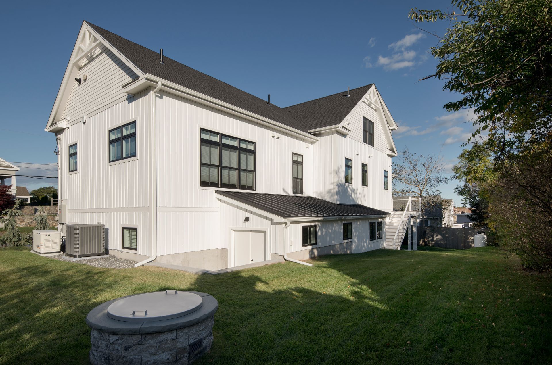 White two-story house with large windows and a green lawn under a blue sky
