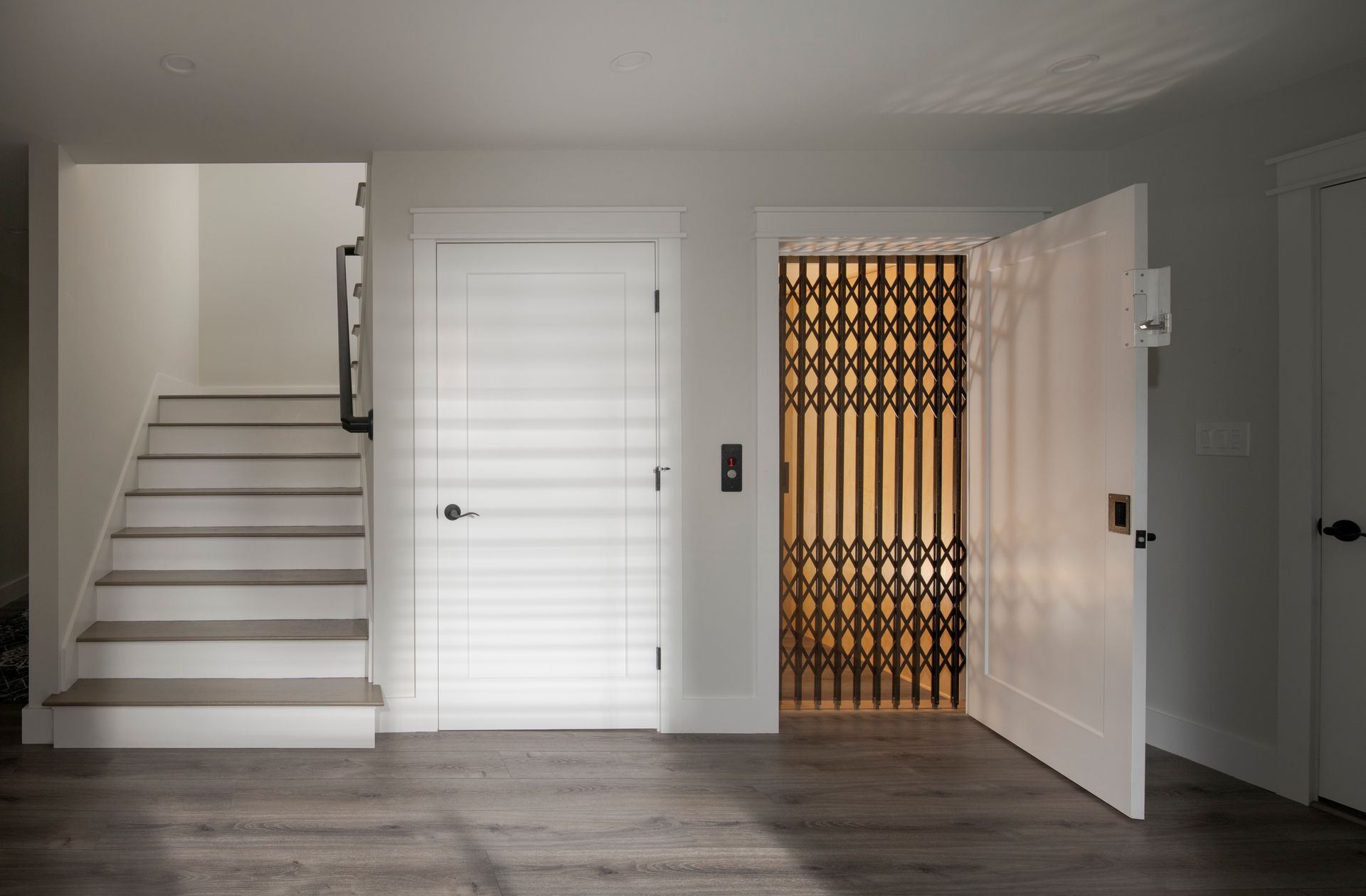 Empty hallway with stairs, white doors, and an open doorway to a gold metal gate area