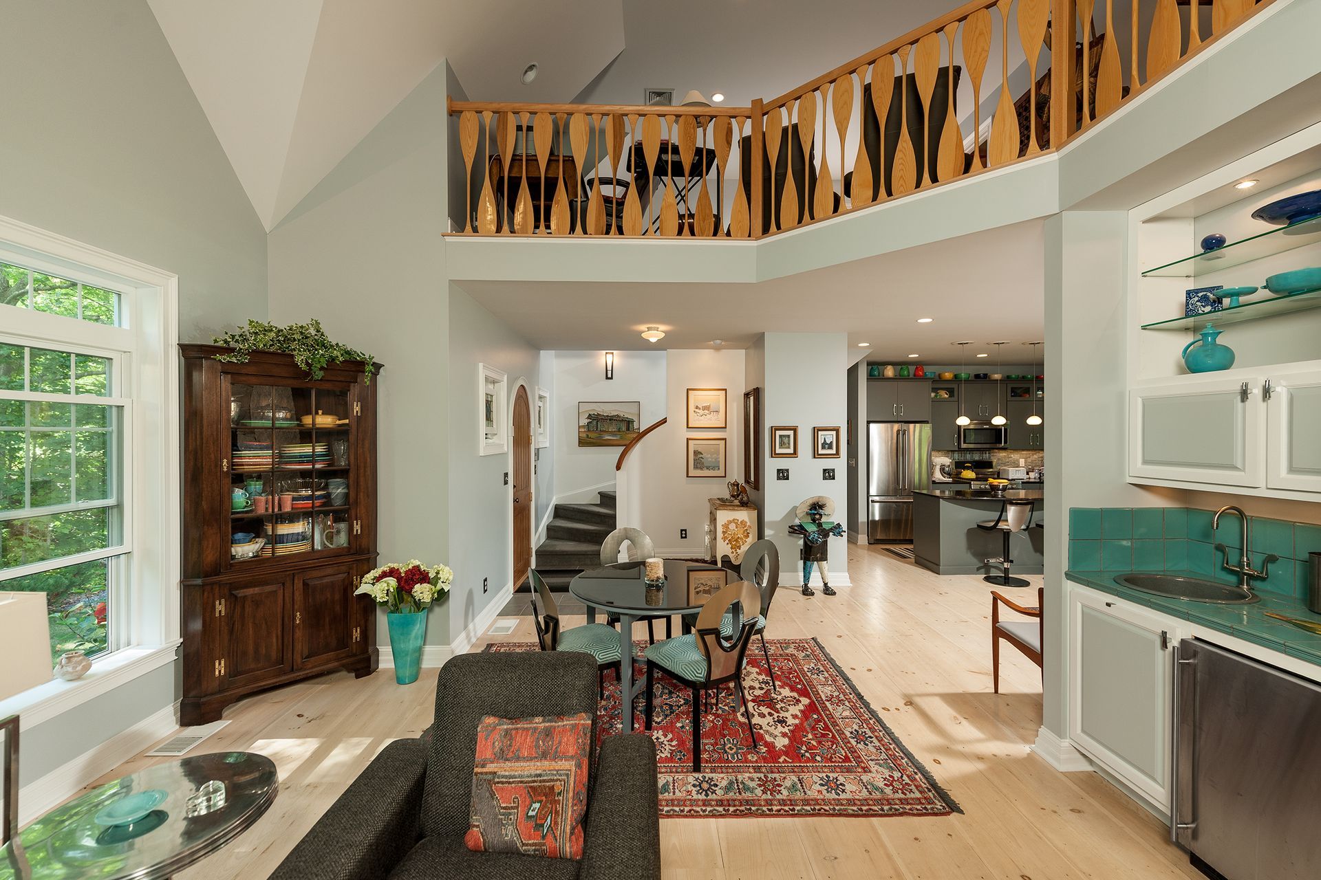 Bright living room with balcony railing, patterned rug, sofas, and shelves in a modern home