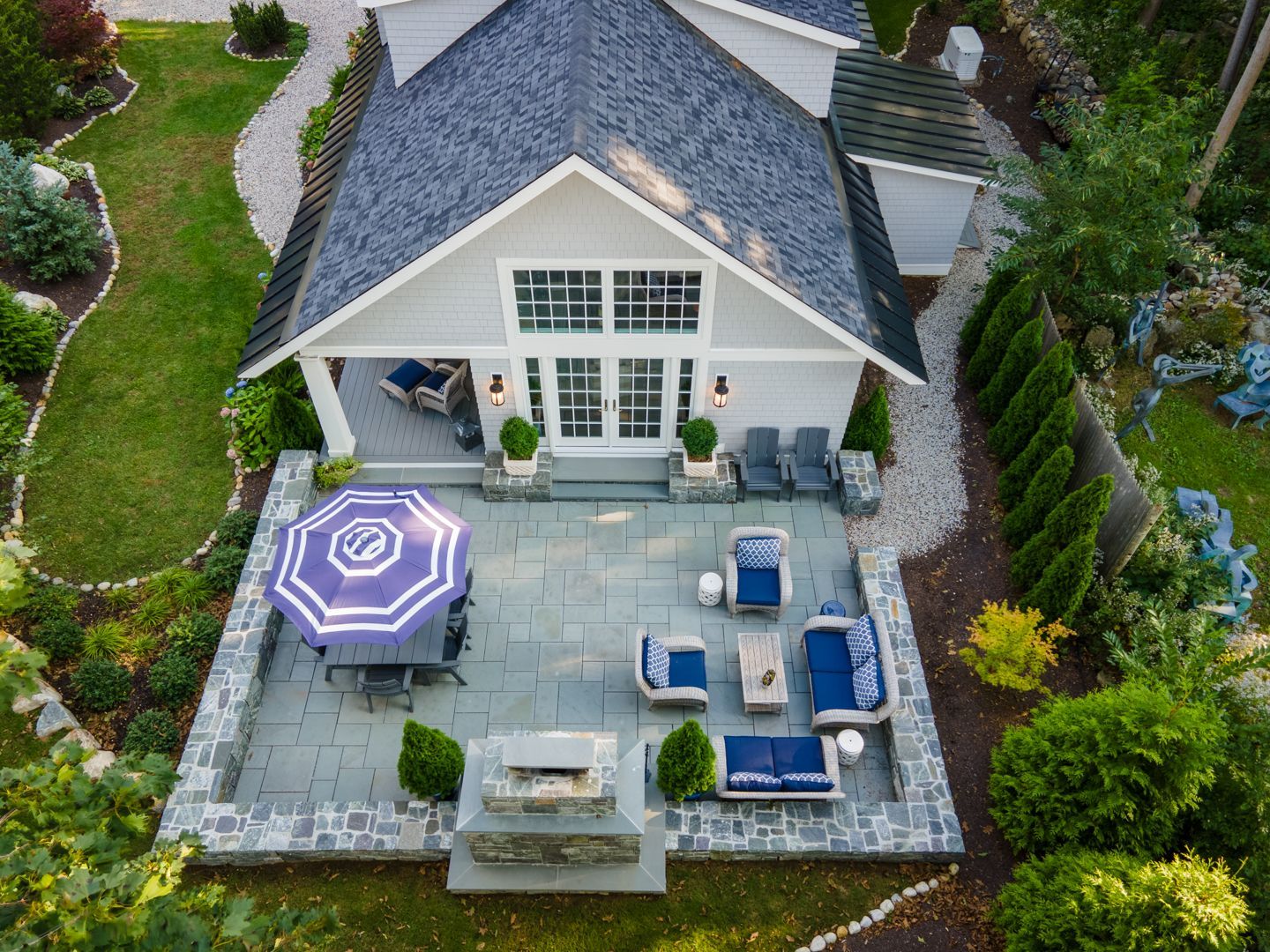 Aerial view of a patio with blue lounge chairs and a purple umbrella beside a house