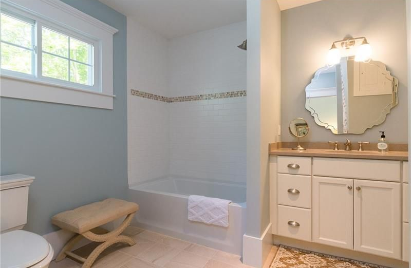 Bright bathroom with a tub, window, vanity, and cream tile accents