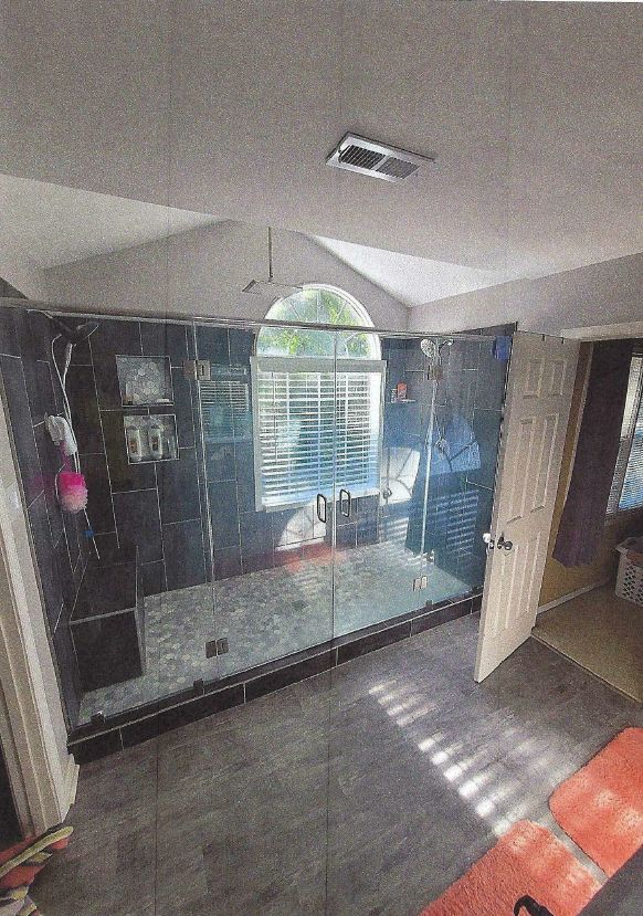 A bathroom with a walk in shower and a window.