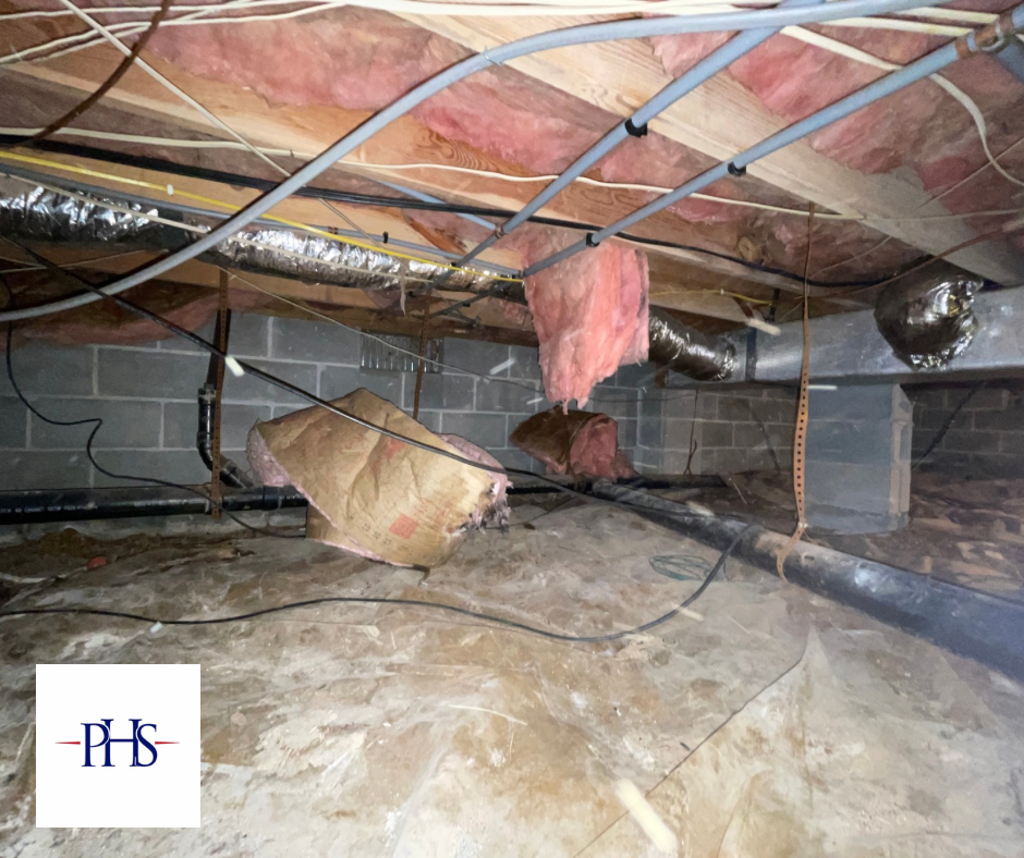 There is a lot of insulation hanging from the ceiling of a basement.