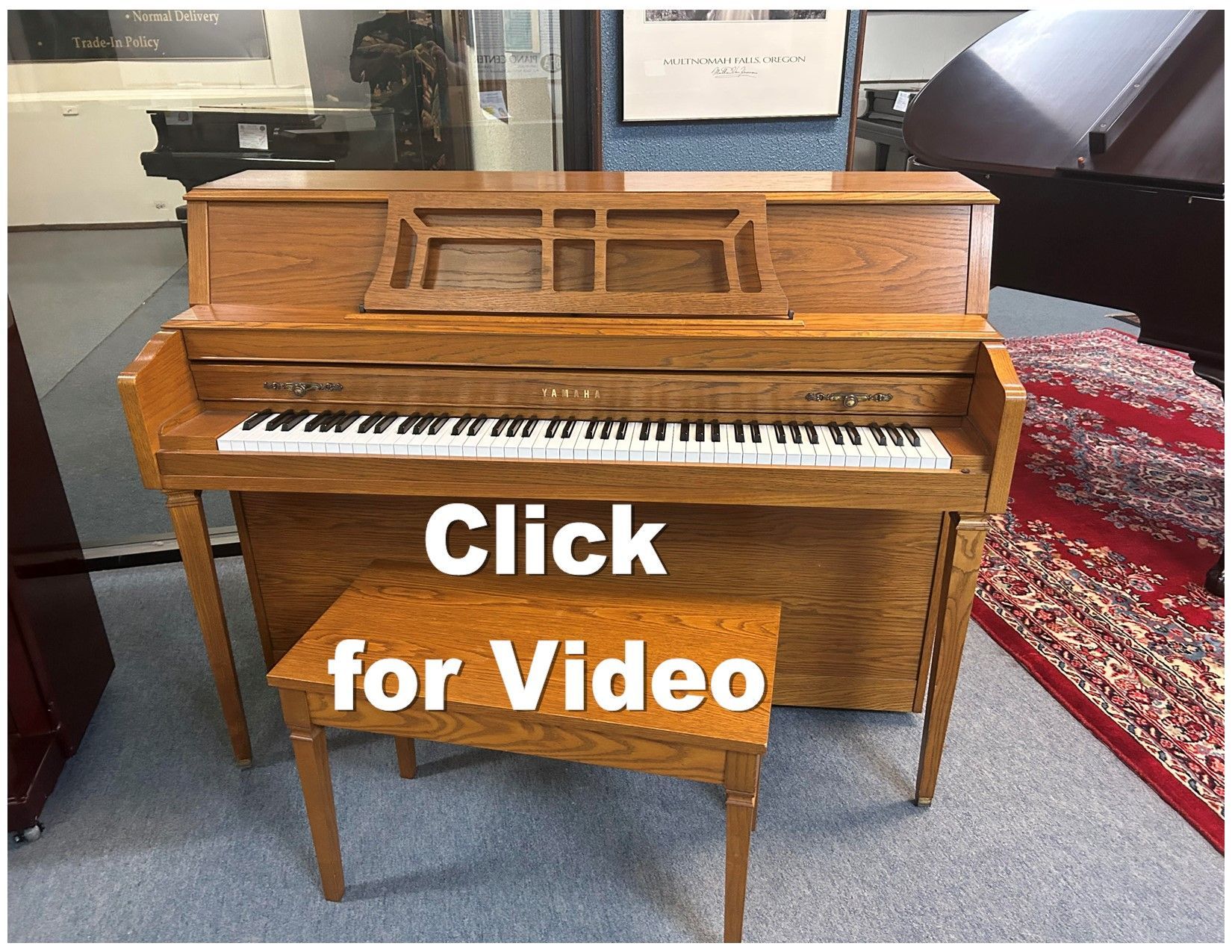 A light oak upright piano with a matching bench. Text overlay reads