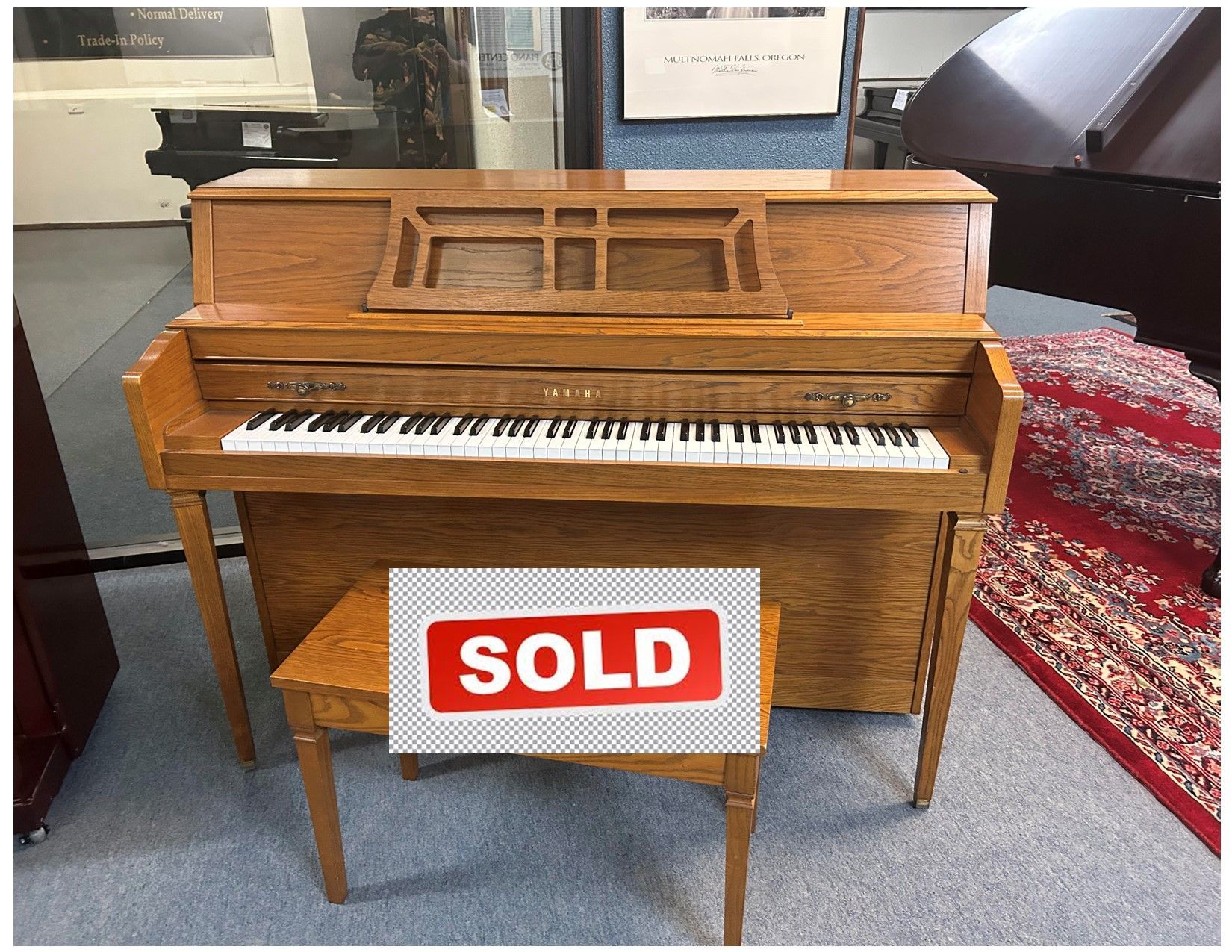 A light oak upright piano with a matching bench. Text overlay reads