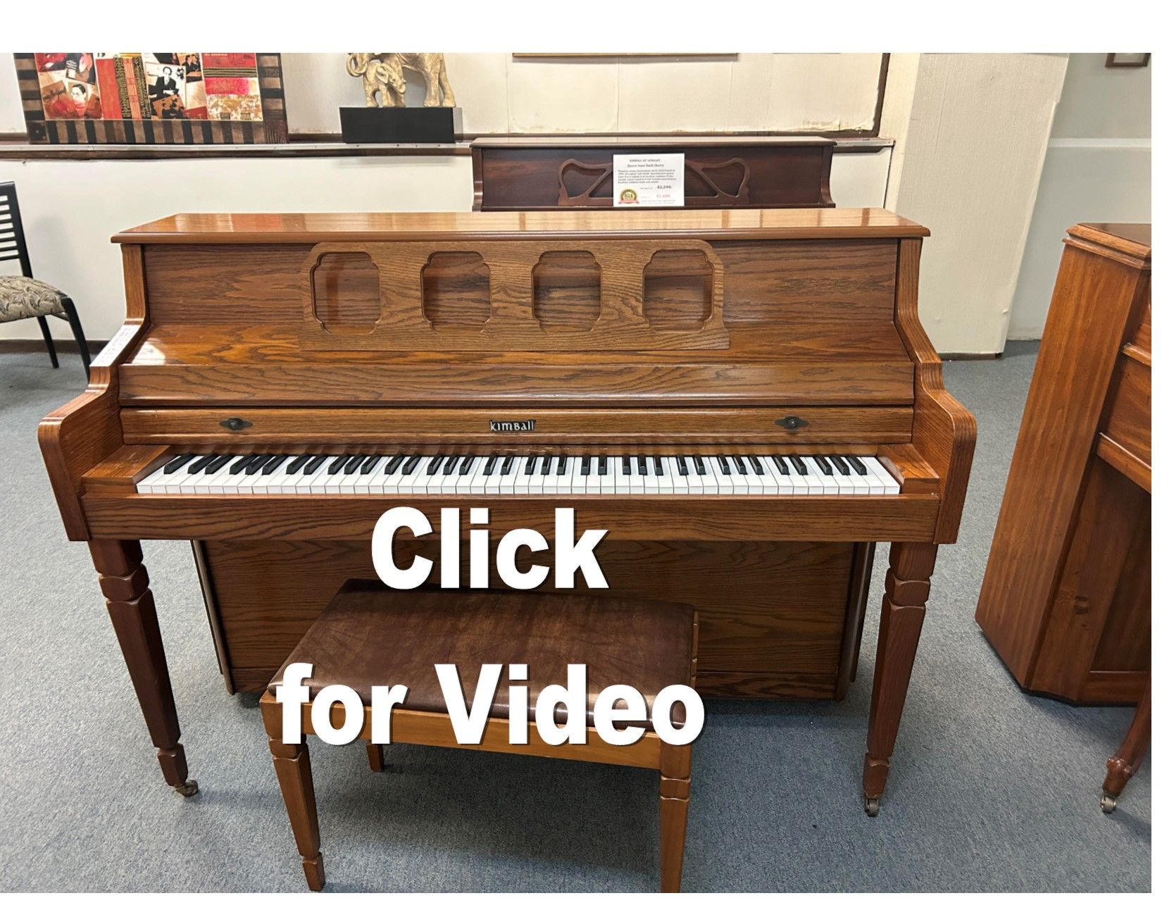 A piano with a bench next to it and the words click for video below it