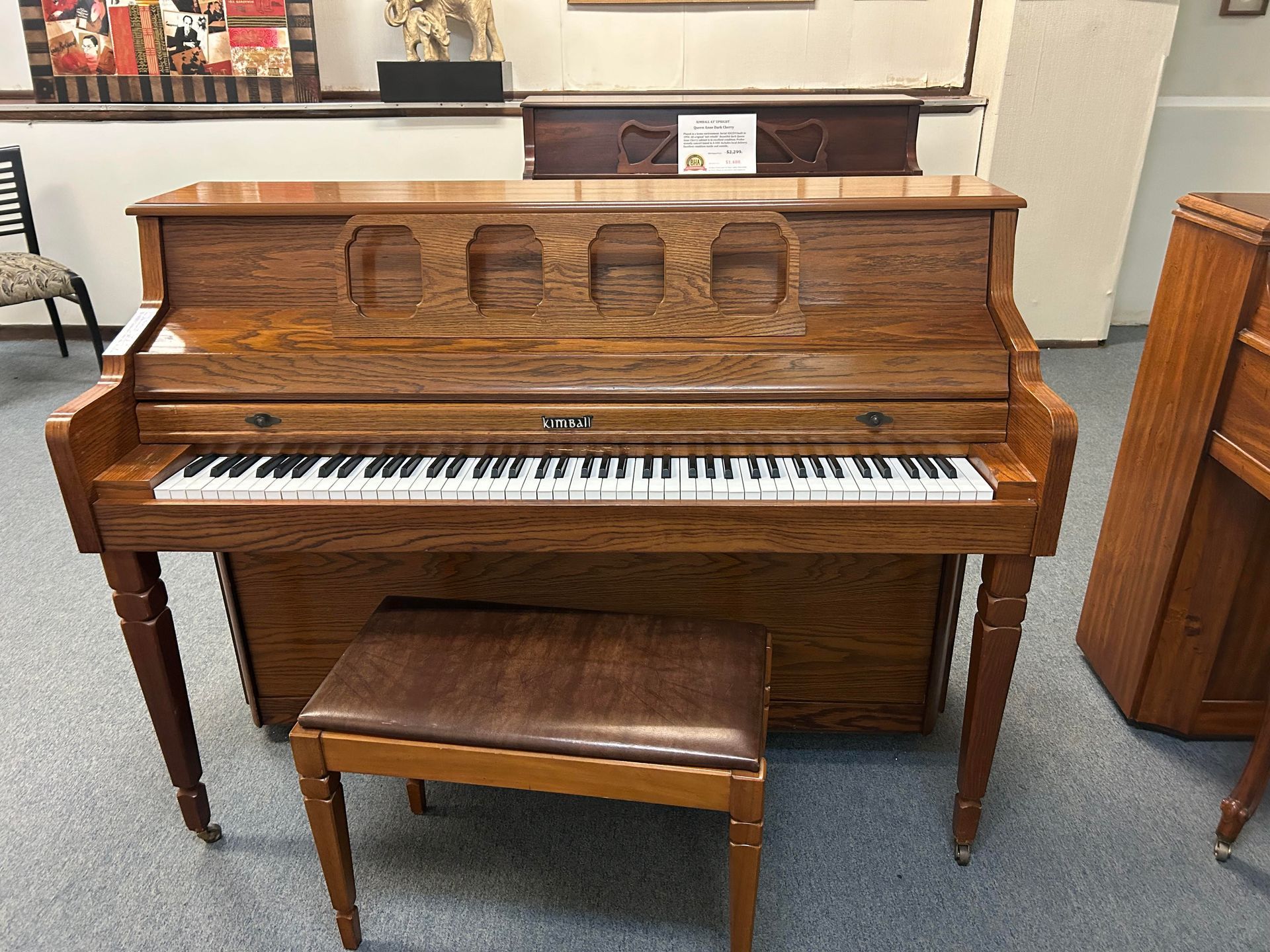 A wooden piano with a stool next to it in a room.