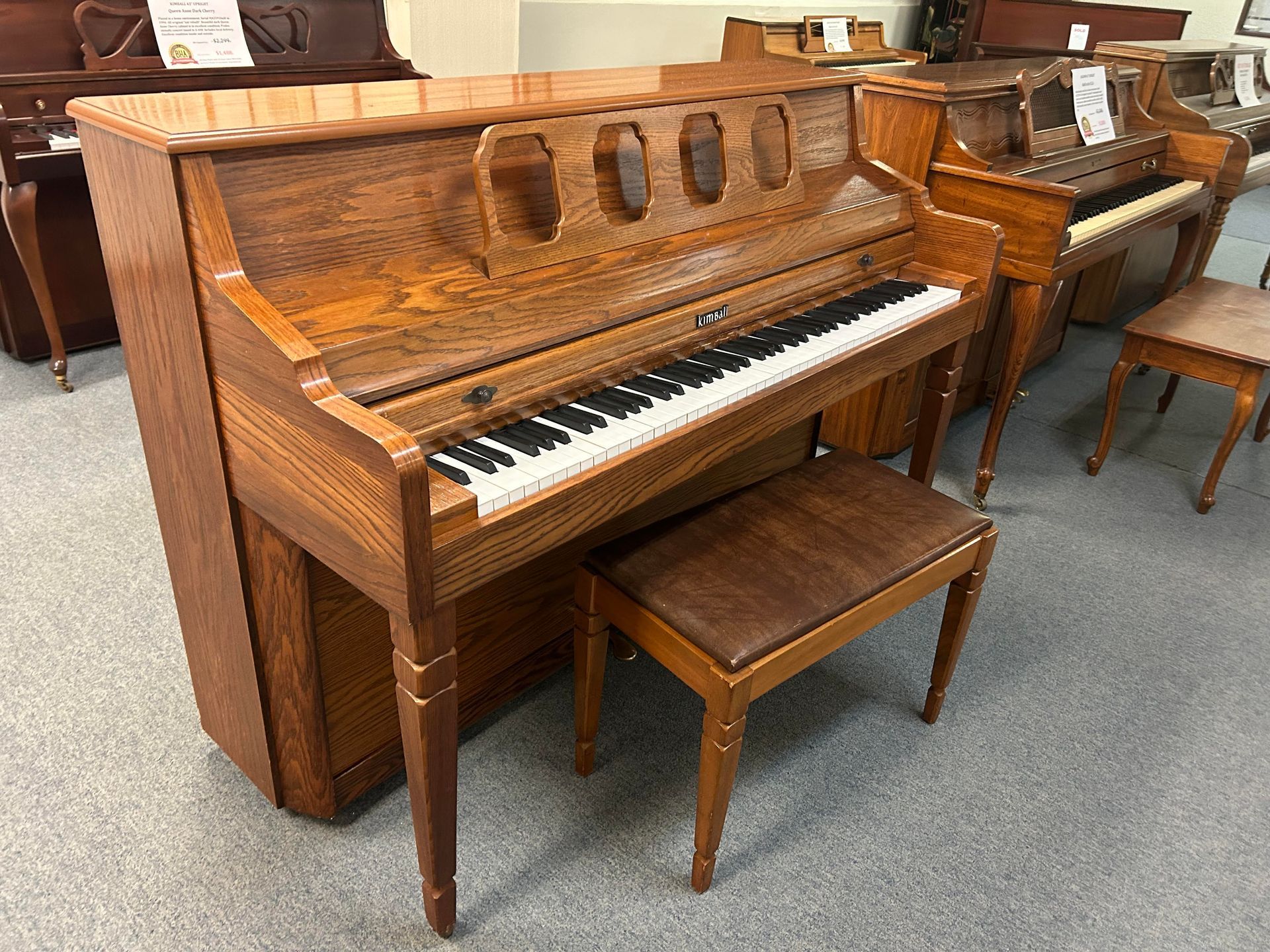 A wooden piano with a bench next to it in a room.