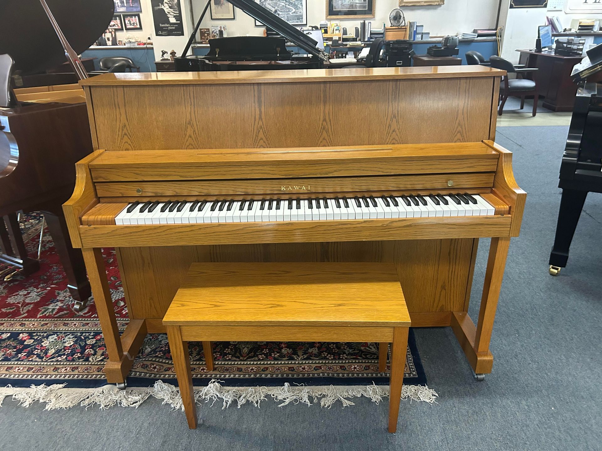 Upright piano with wooden finish and matching bench, indoors. 