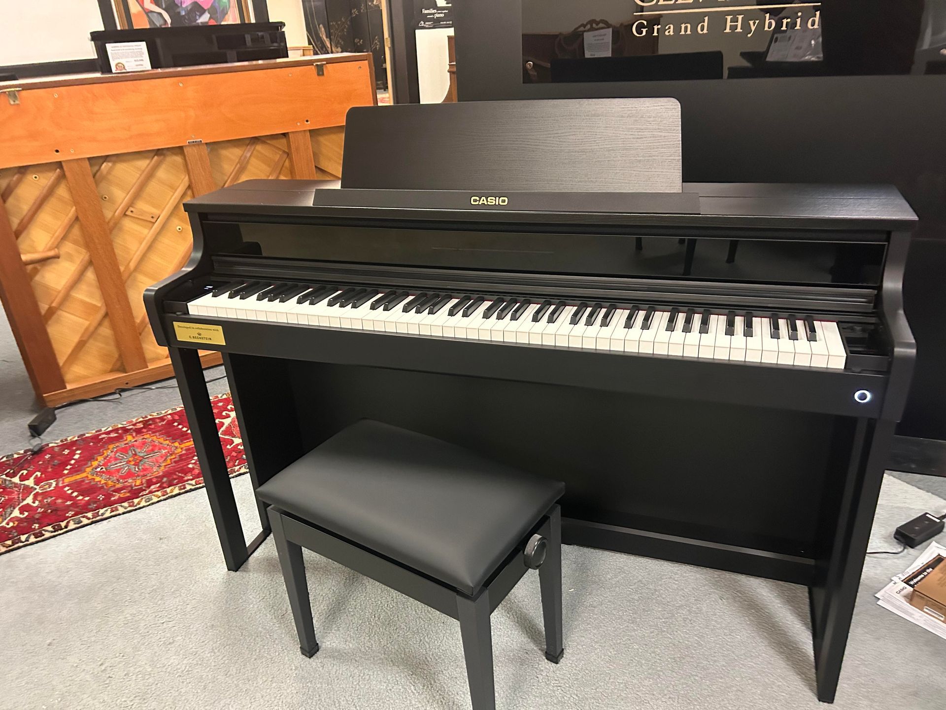 A black piano with a stool next to it in a room.