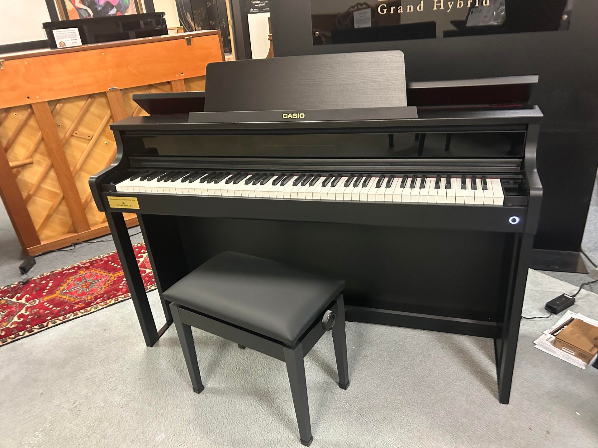 A black piano with a stool next to it in a room.