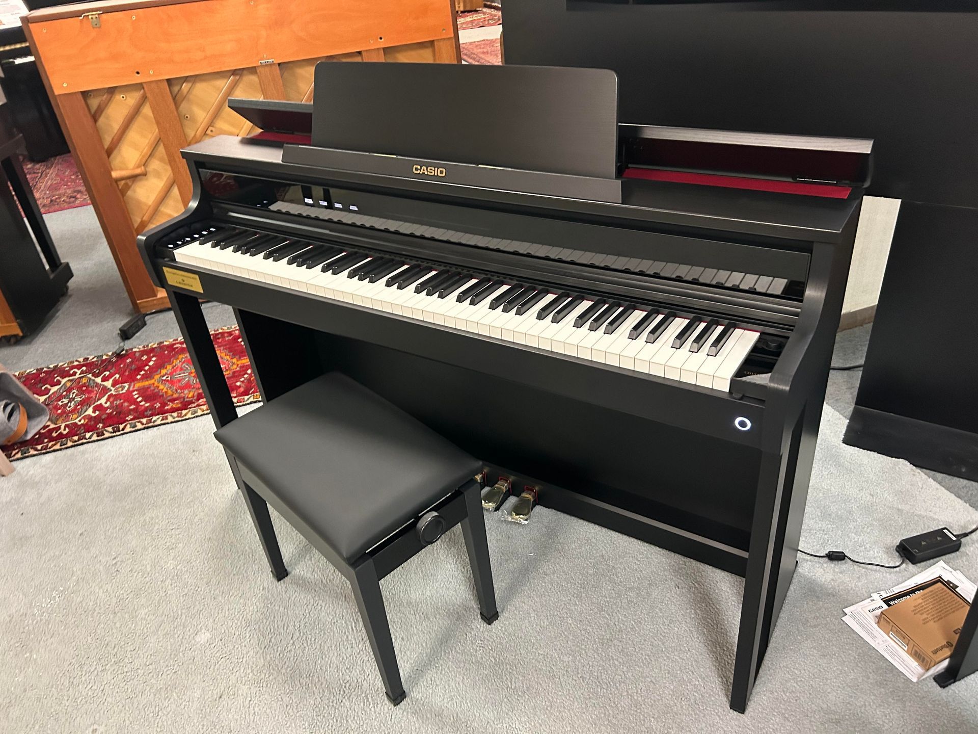 A black piano with a stool next to it in a room.