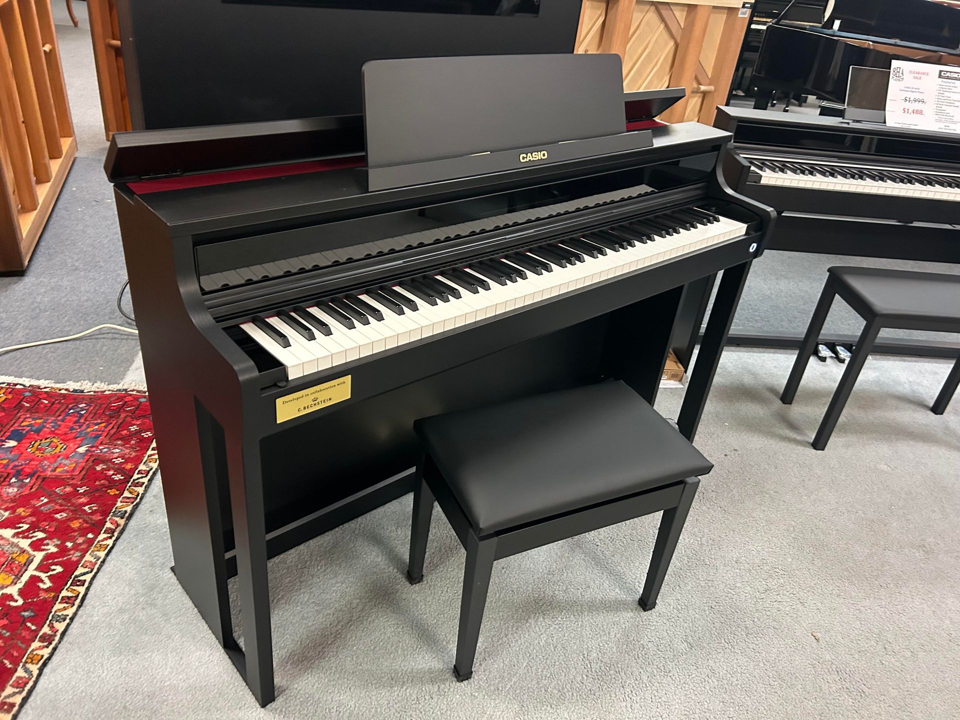 A black piano with a stool next to it in a room.