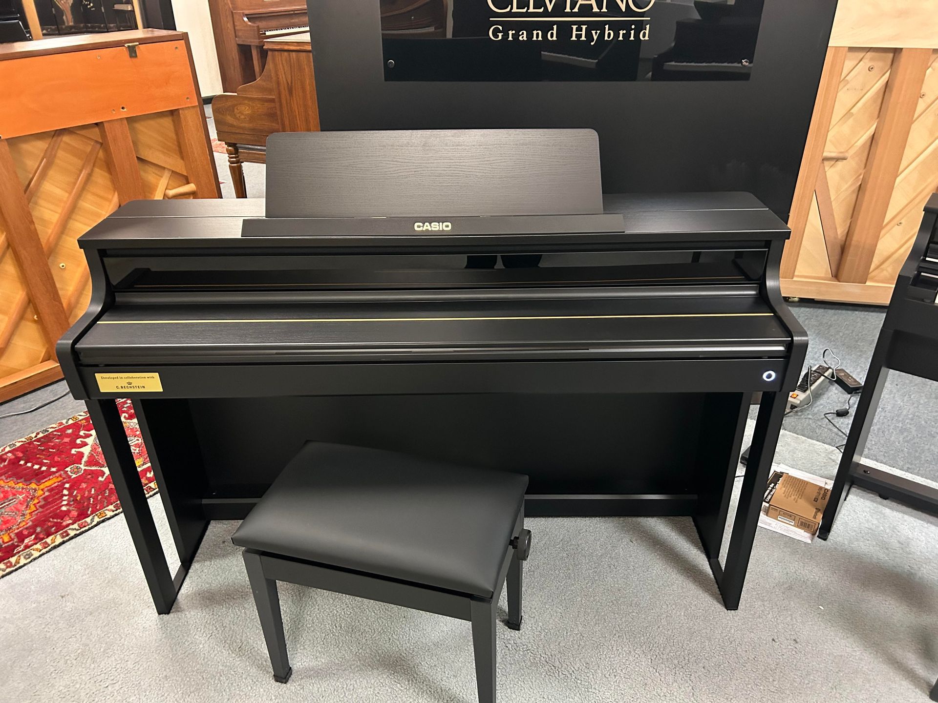 A black piano with a stool next to it in a room.