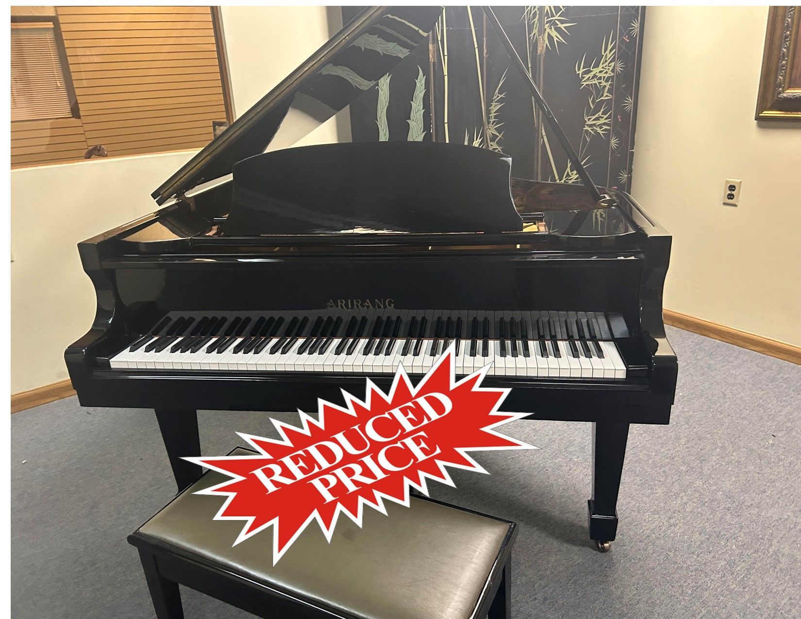 Grand piano with open lid and stool in a room. Click for Video text overlay.