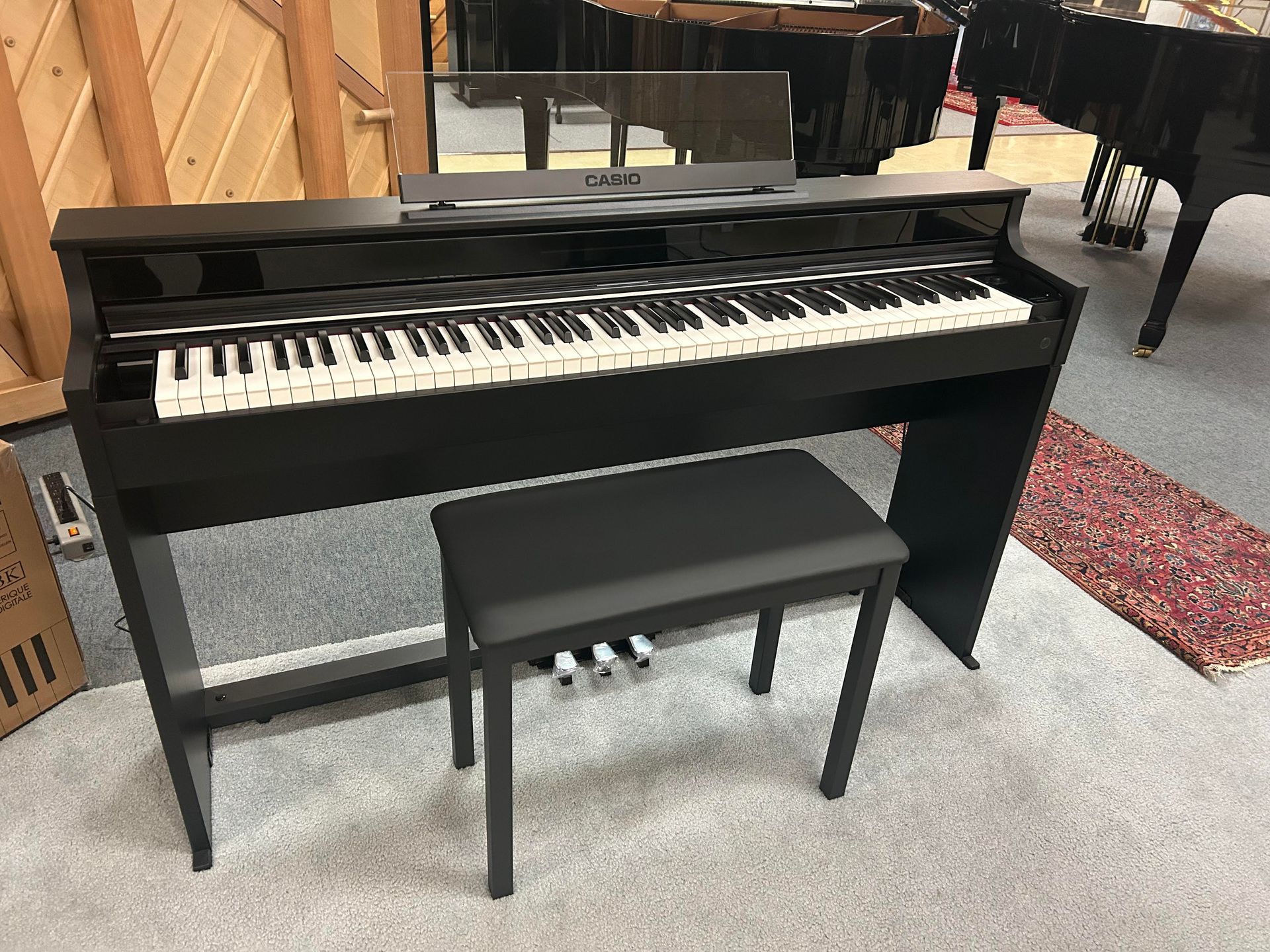 A black piano with a bench next to it in a room.