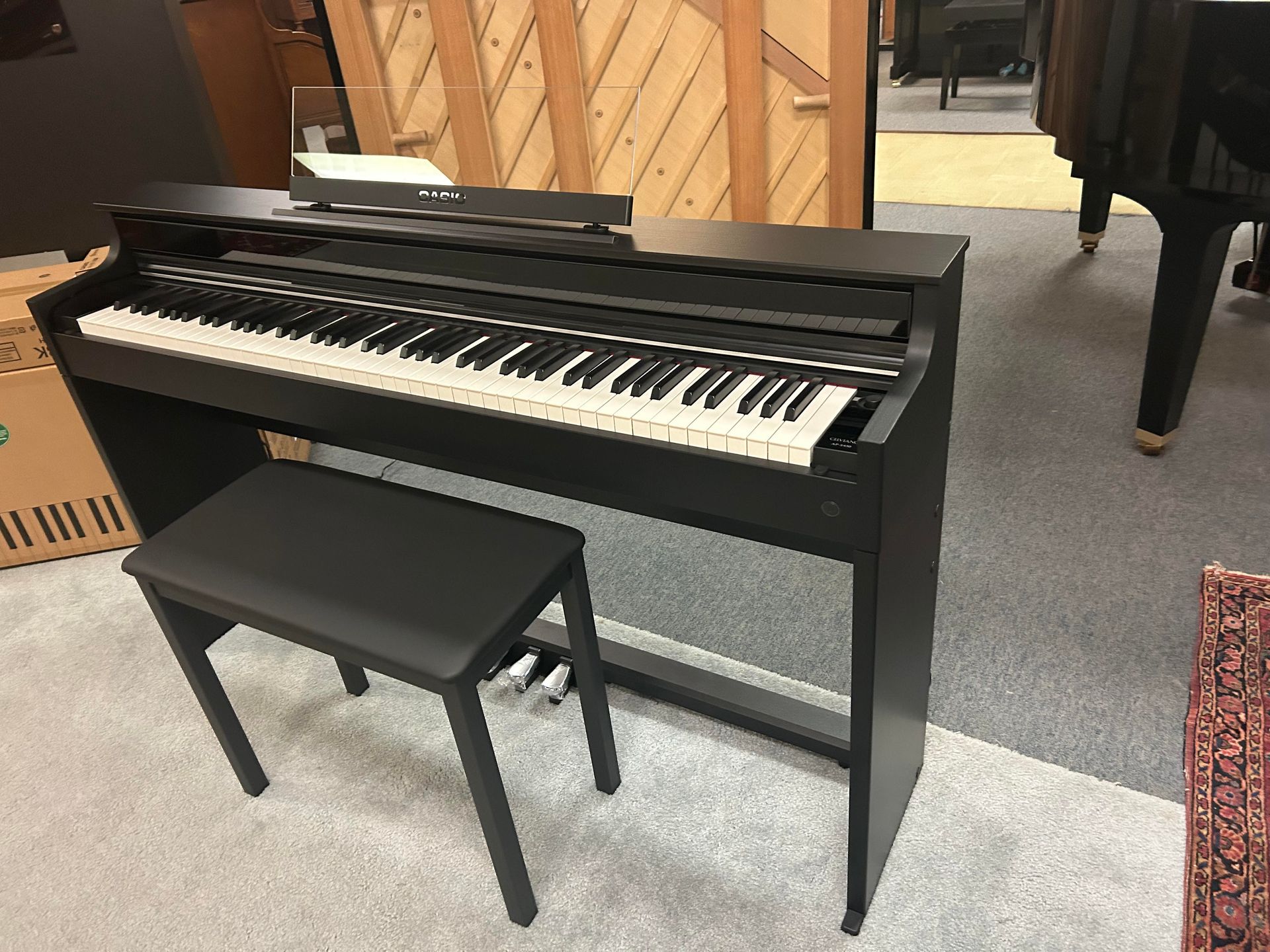 A black piano with a bench next to it in a room.