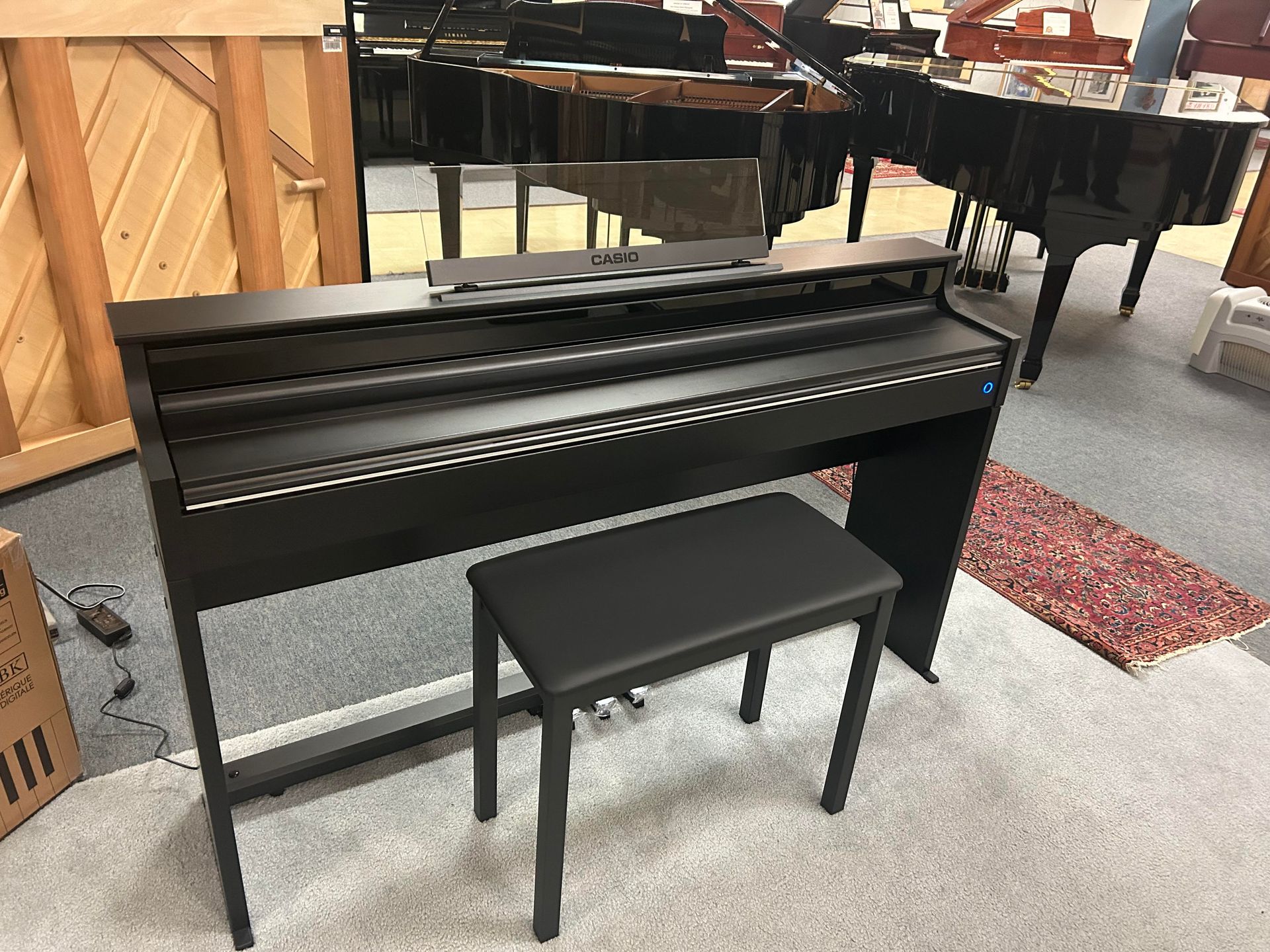 A black piano with a bench next to it in a room.
