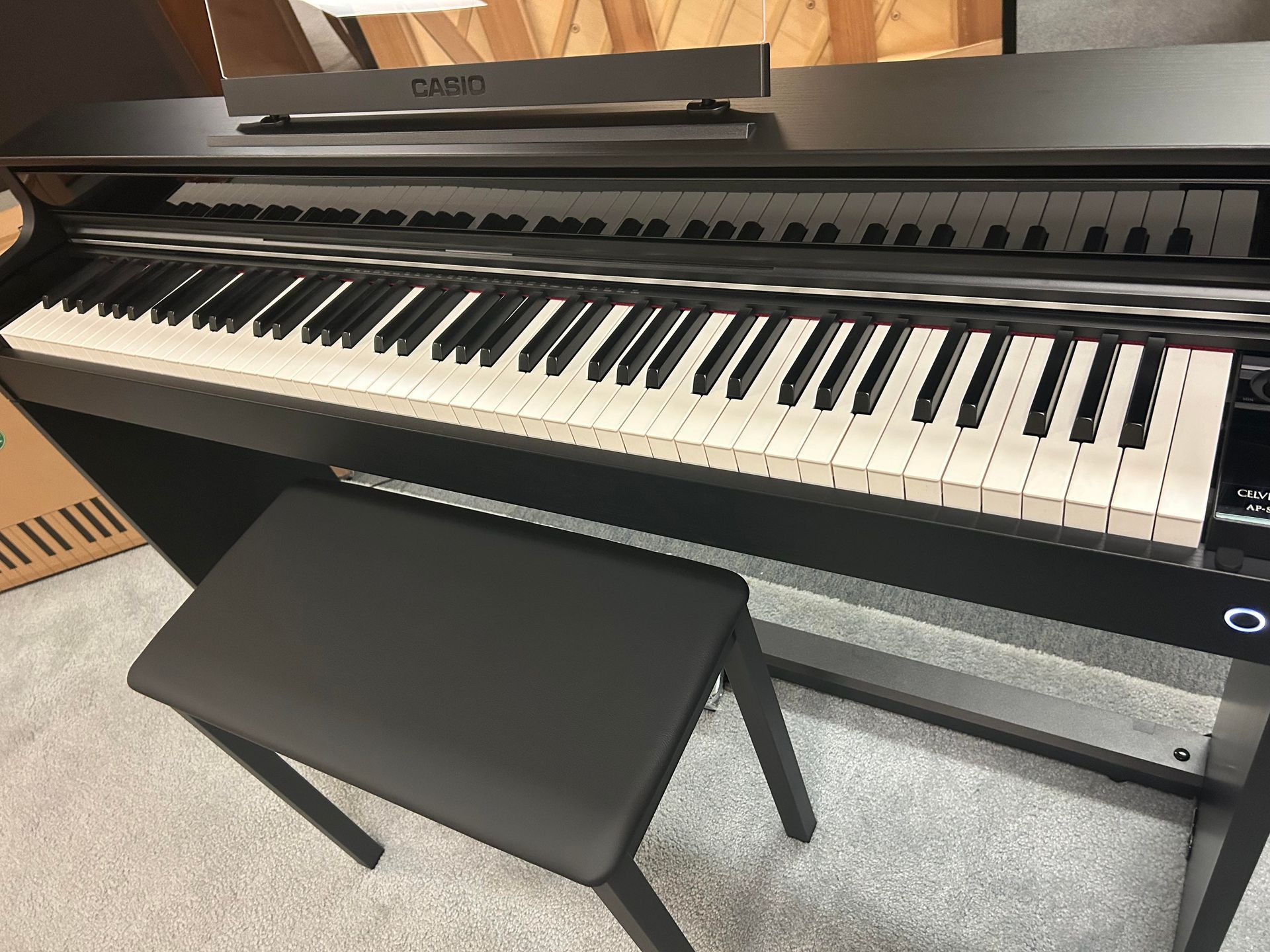 A piano keyboard with a bench next to it.