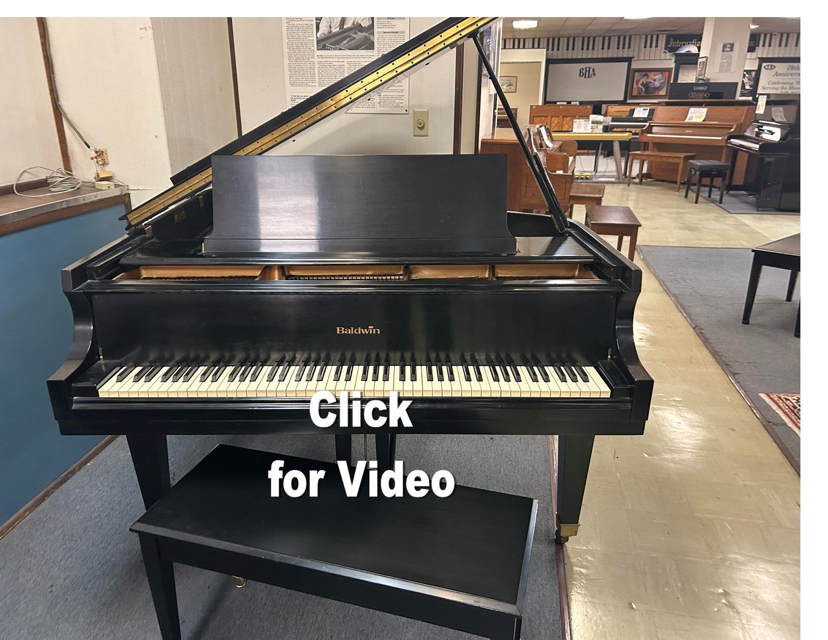 Black grand piano in a music store, with a bench. 