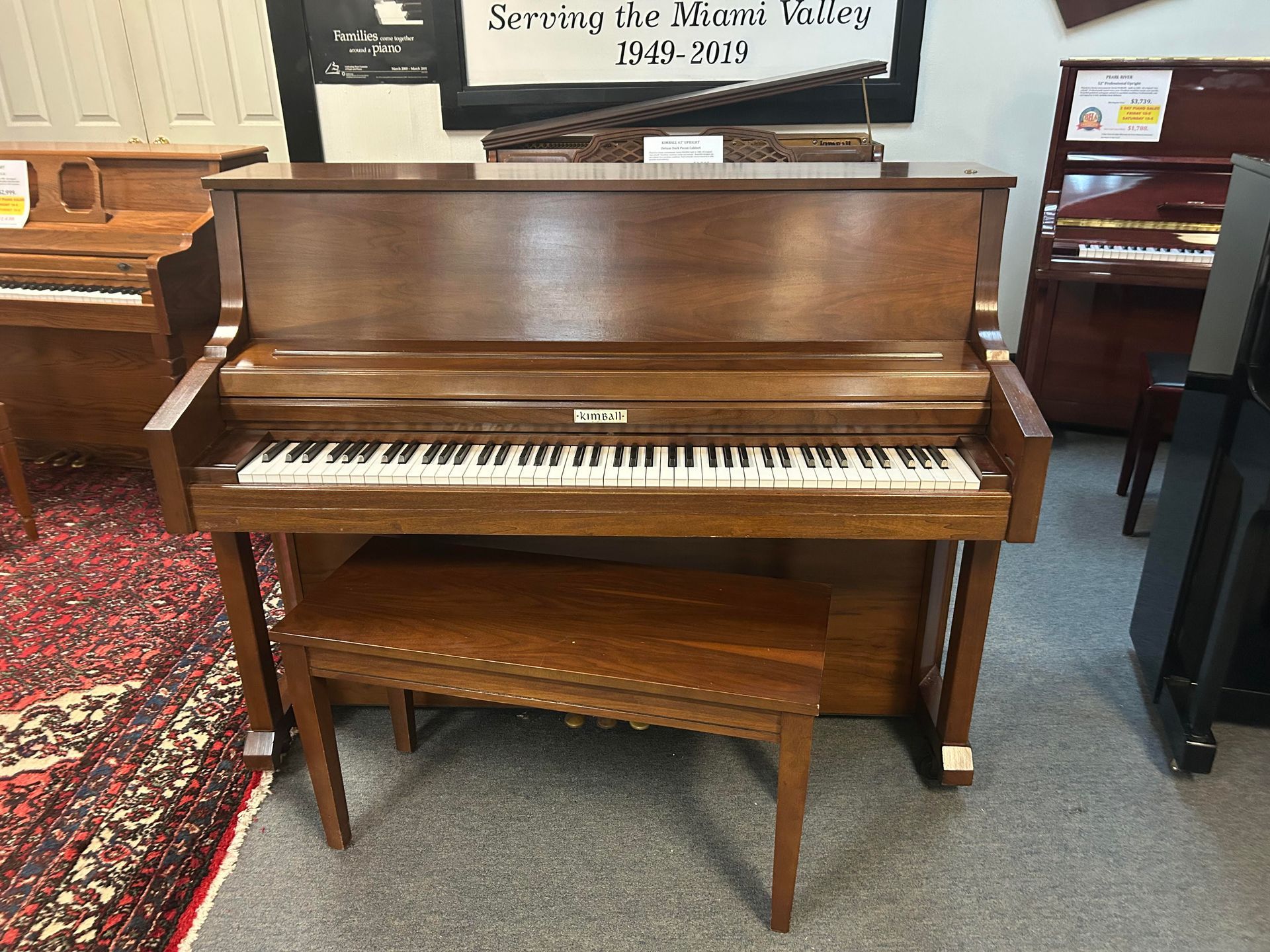 A brown Kimball Upright piano with a bench and visible keys