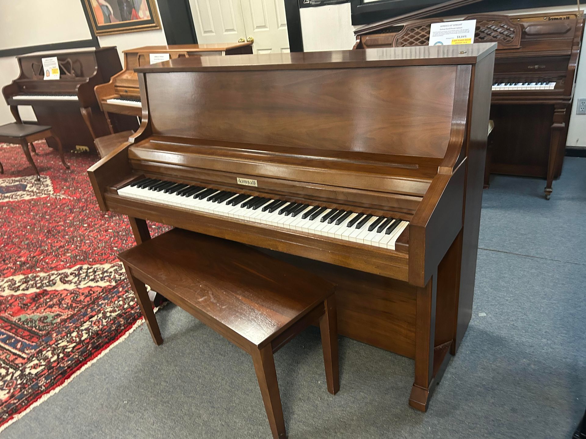 A brown Kimball Upright piano with a bench and visible keys