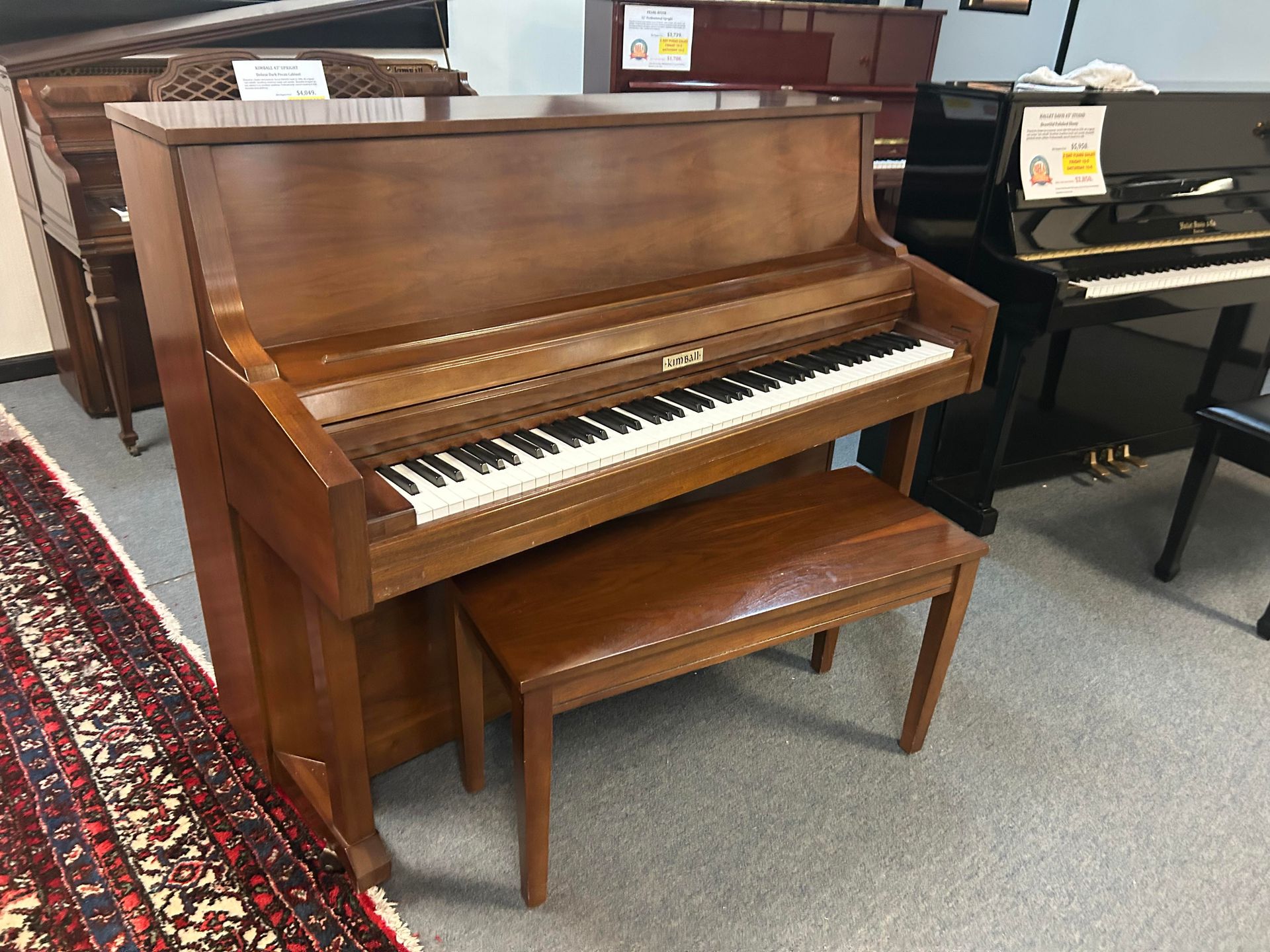A brown Kimball Upright piano with a bench and visible keys