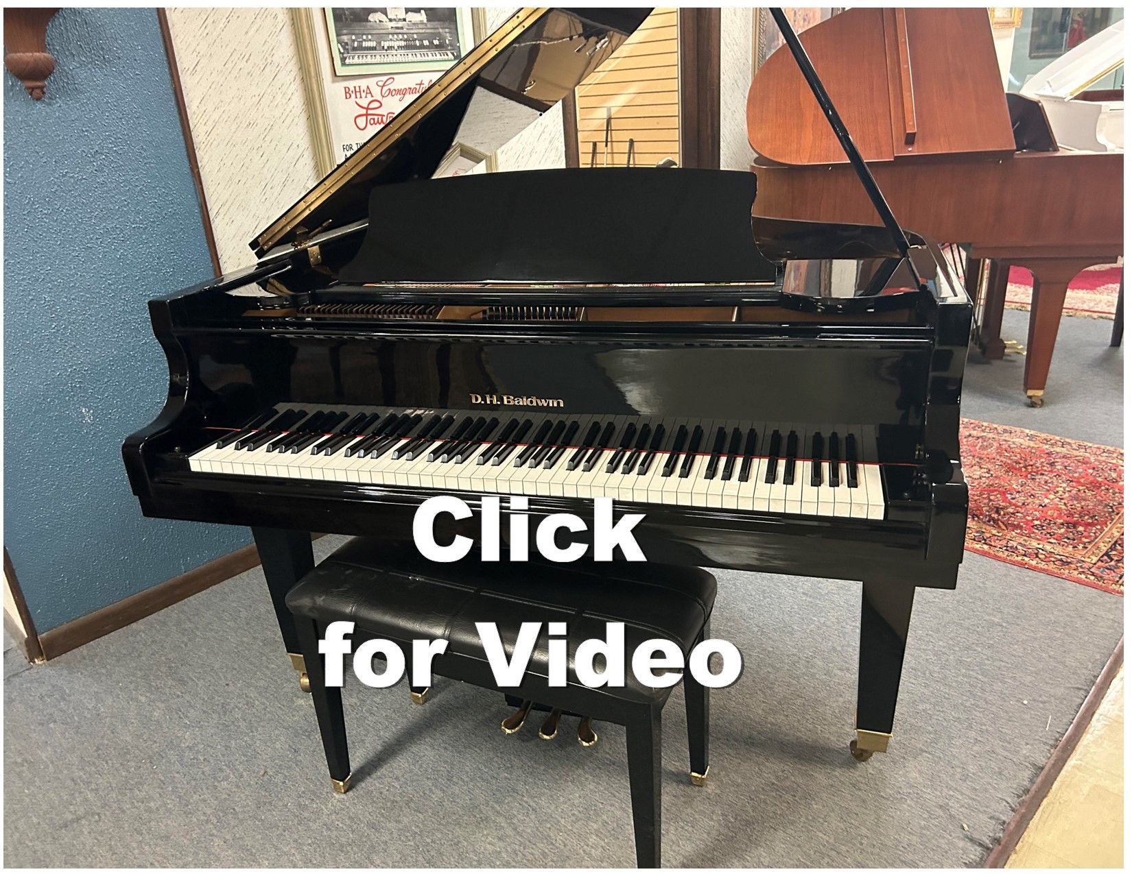 A black grand piano is sitting in a room next to a stool.