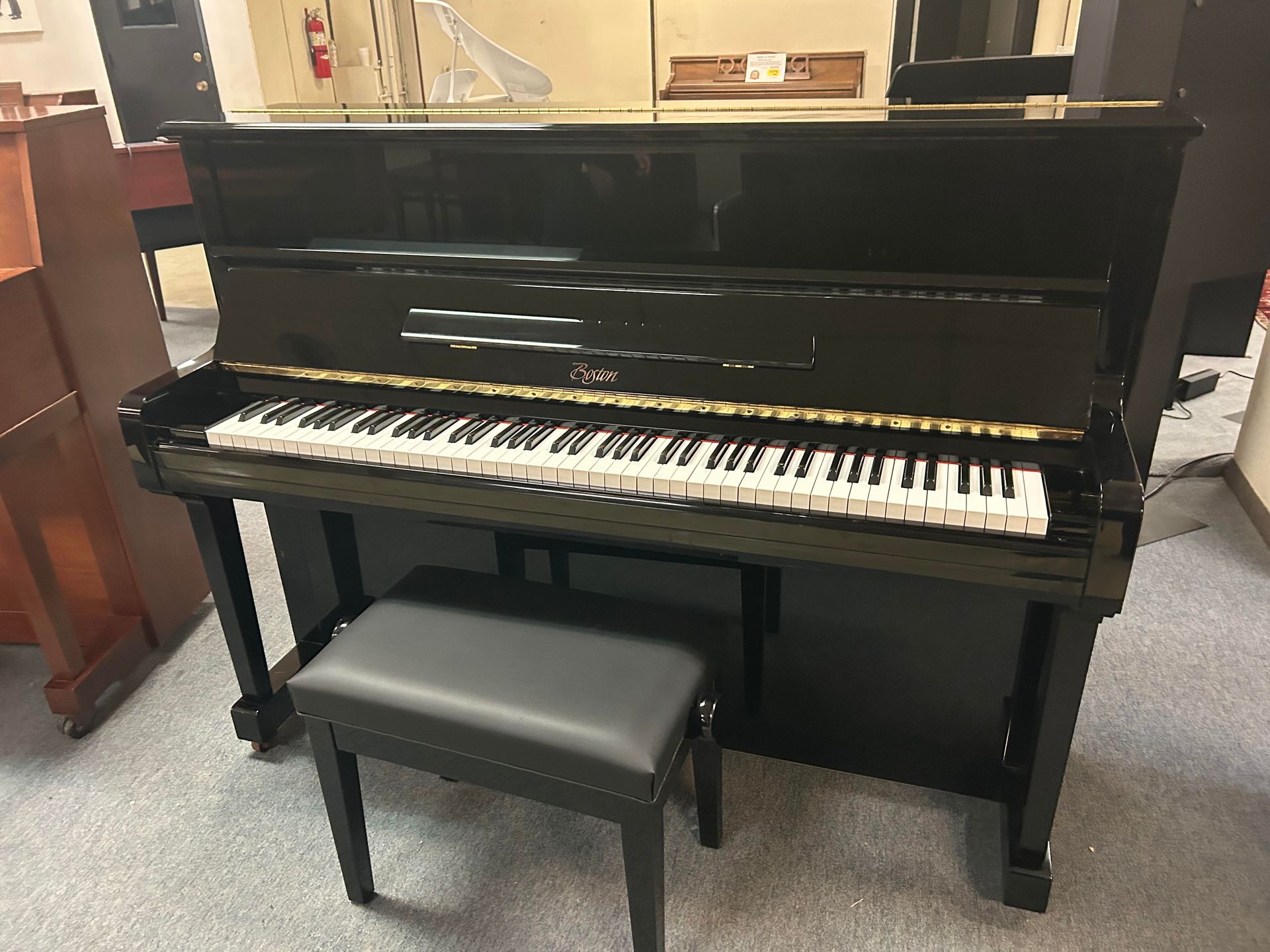 A black piano with a black bench next to it in a room.