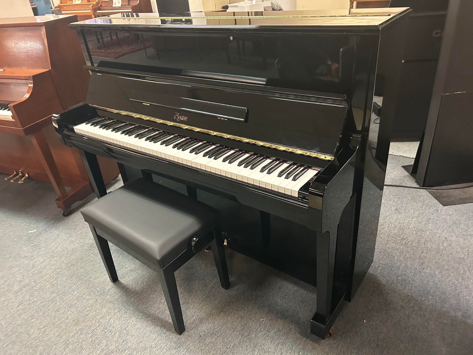 A black upright piano with a stool next to it in a room.