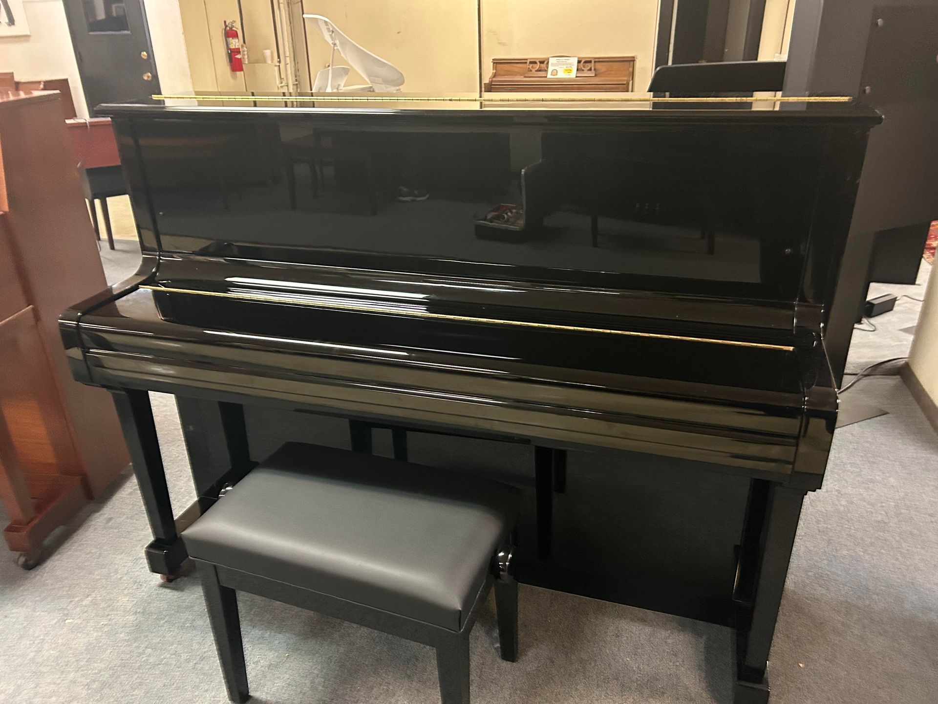 A black piano with a stool next to it in a room.