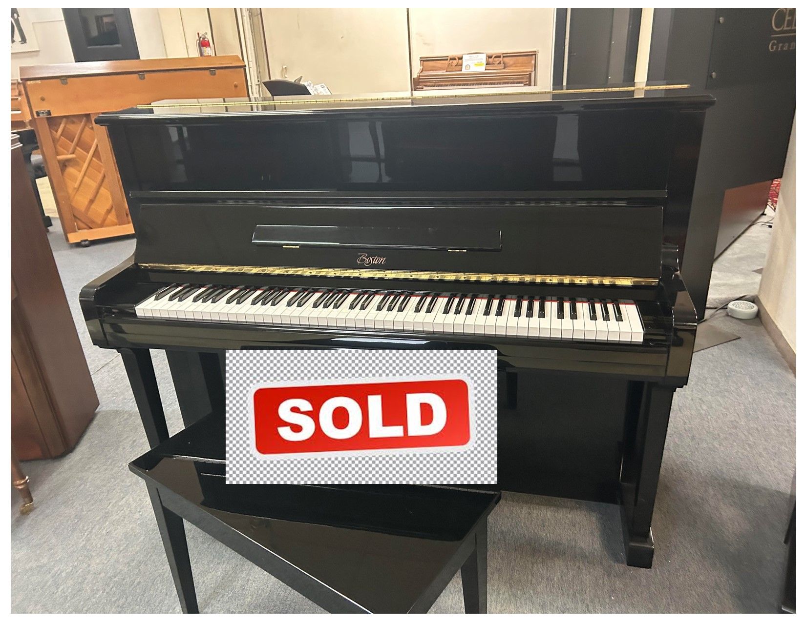 A black upright piano with a stool underneath it.