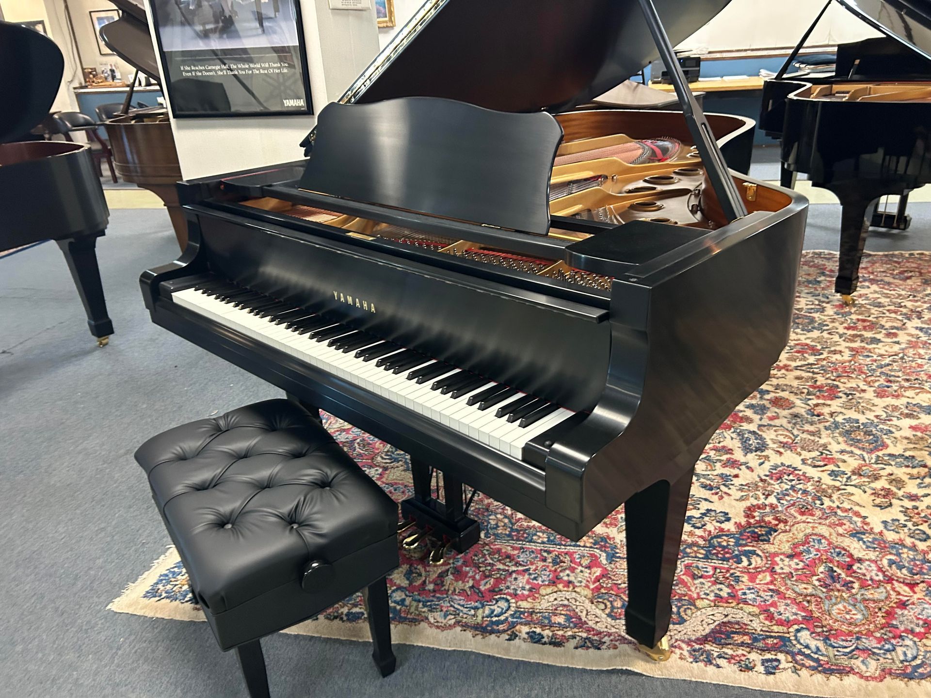 Black grand piano with a bench, in a showroom.
