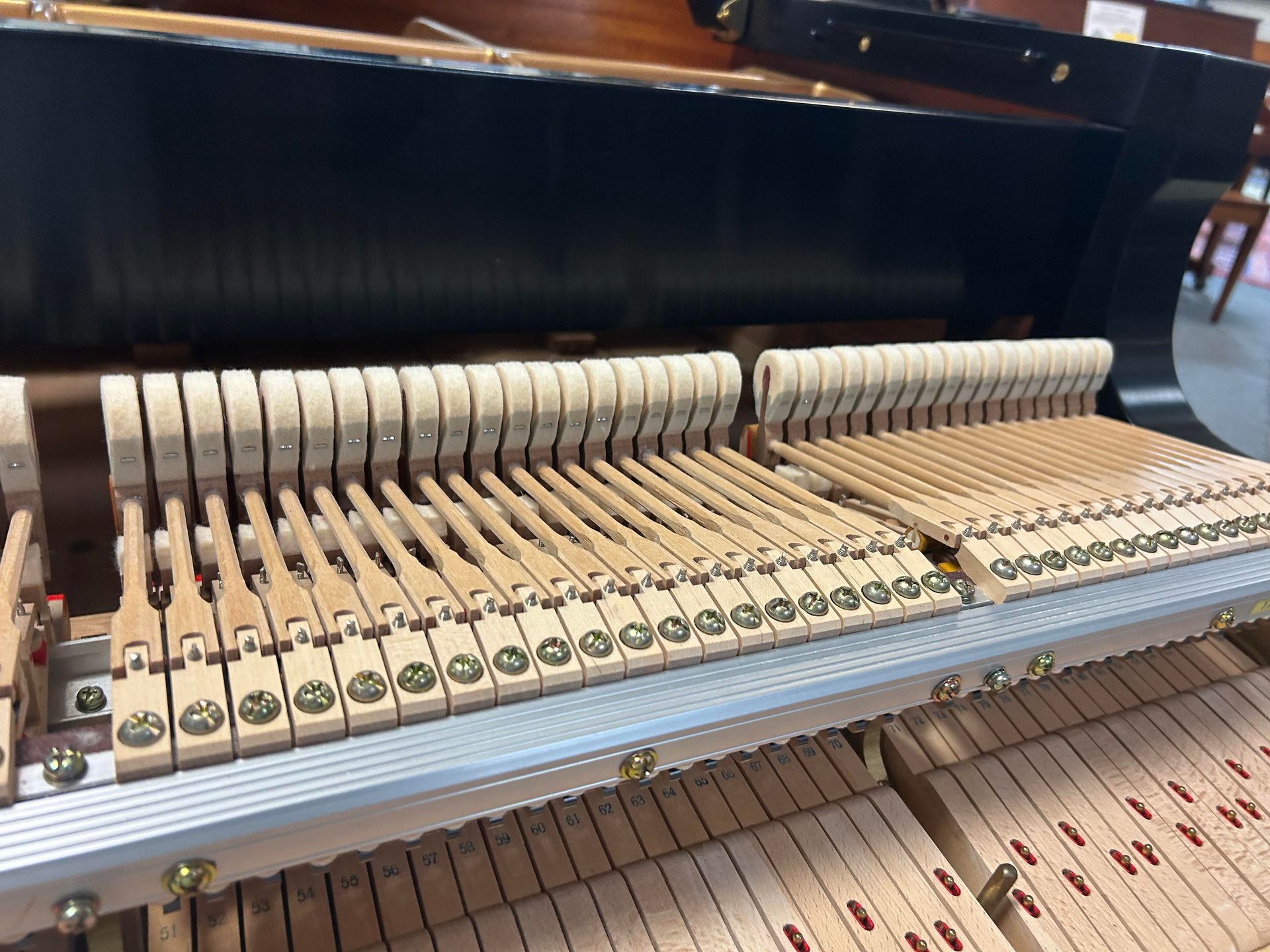 Piano's internal mechanism: hammers and dampers arranged inside, mostly beige wood, metal, and black backing.