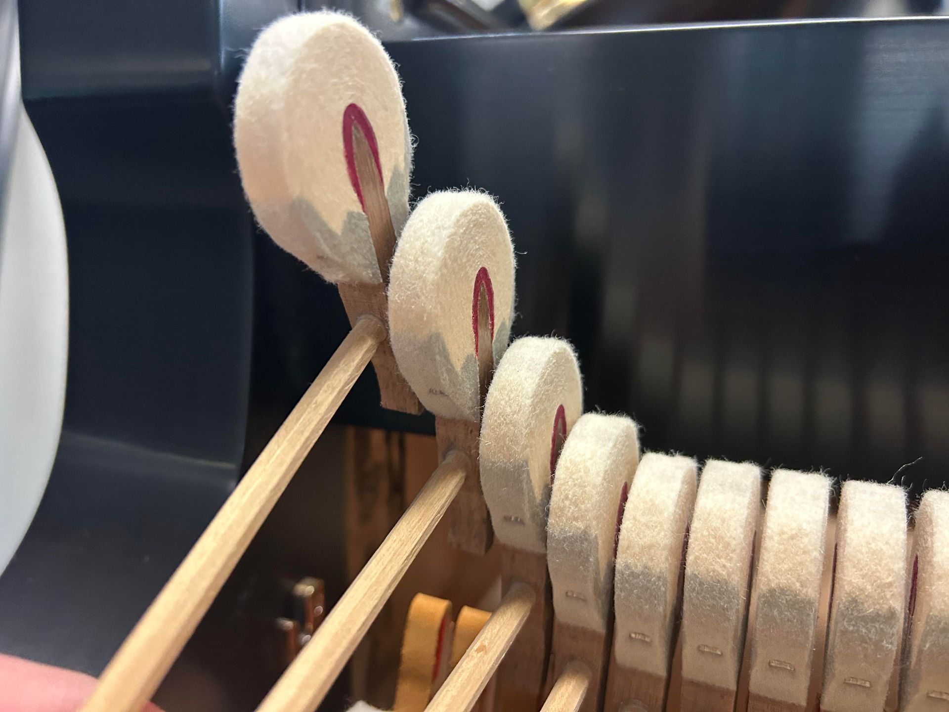 Close-up of piano hammers. Cream-colored felt on wooden hammers. Black interior background.