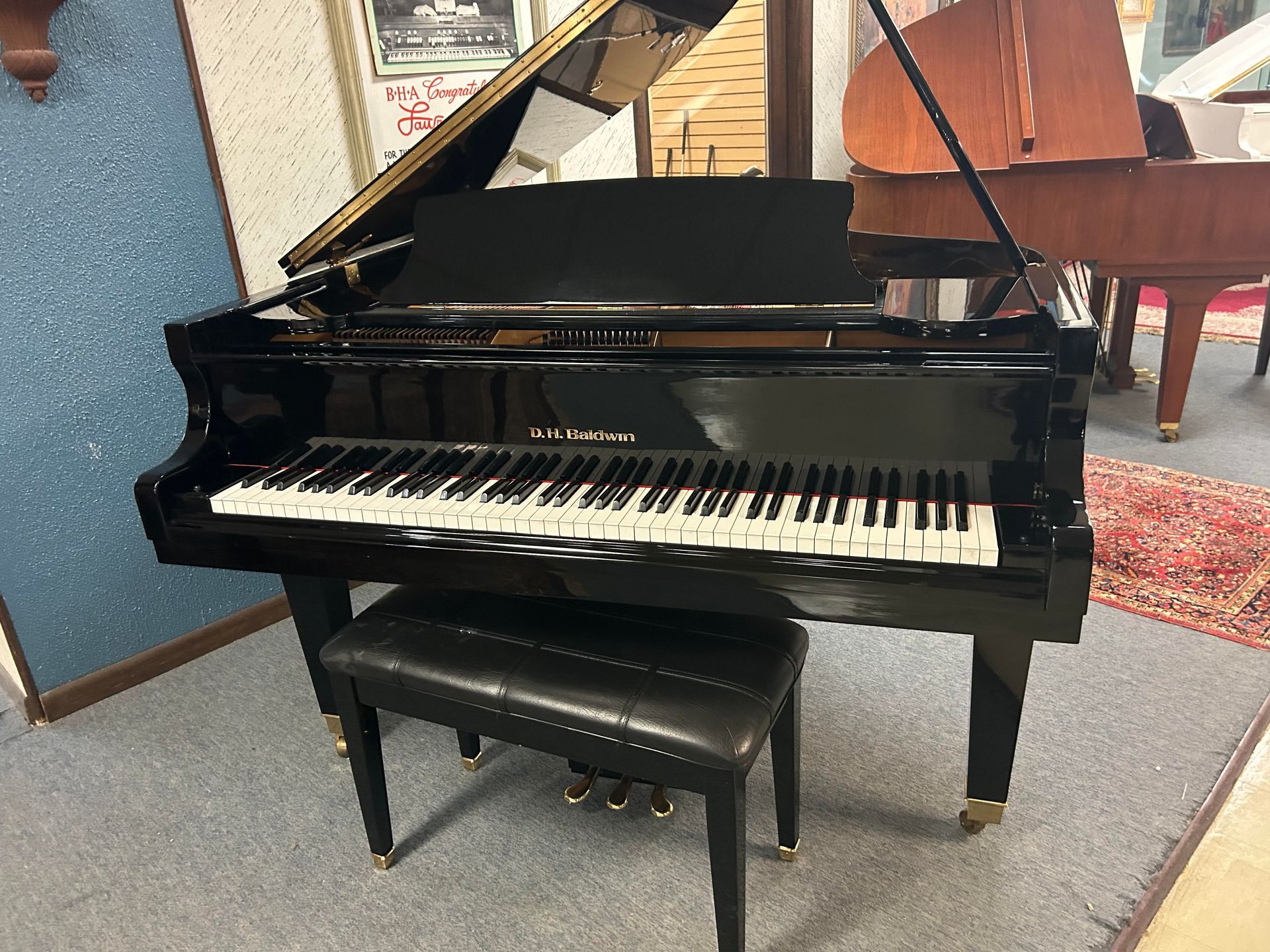 A black grand piano with a bench next to it in a room.