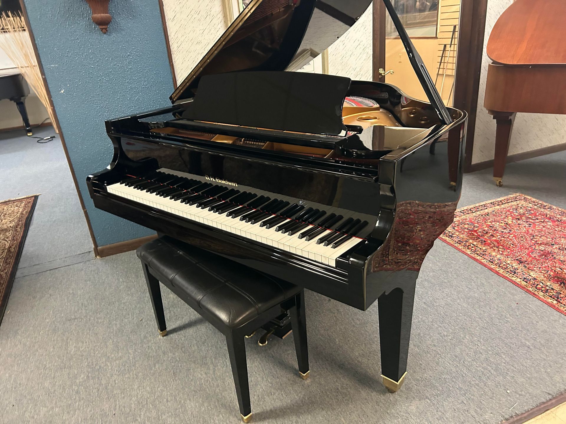 A black grand piano is sitting in a room with a bench.