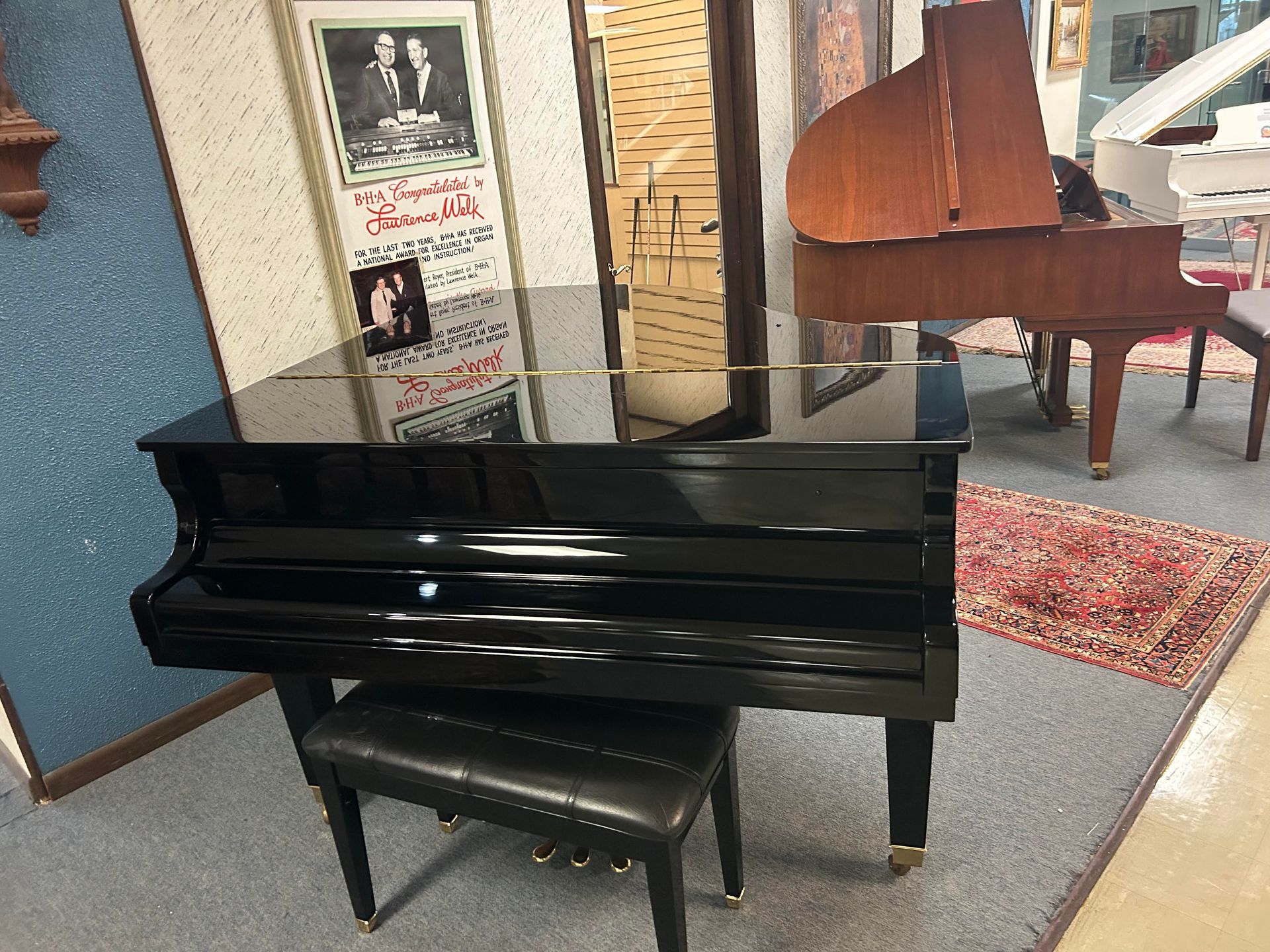 A black grand piano is sitting in a room with other pianos.