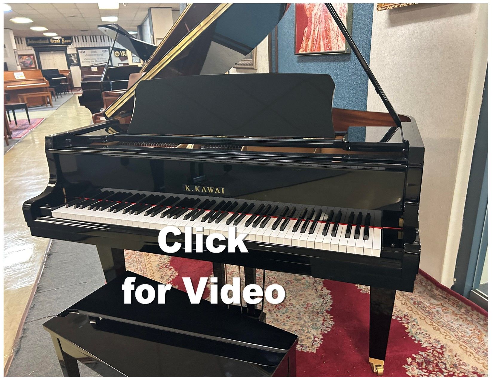 Black grand piano with open lid and bench, in a showroom.