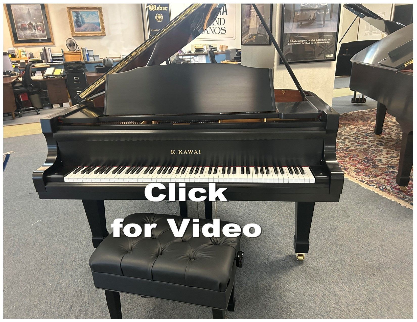 Black grand piano with black leather bench in a showroom, “Video Coming Soon” overlaid.