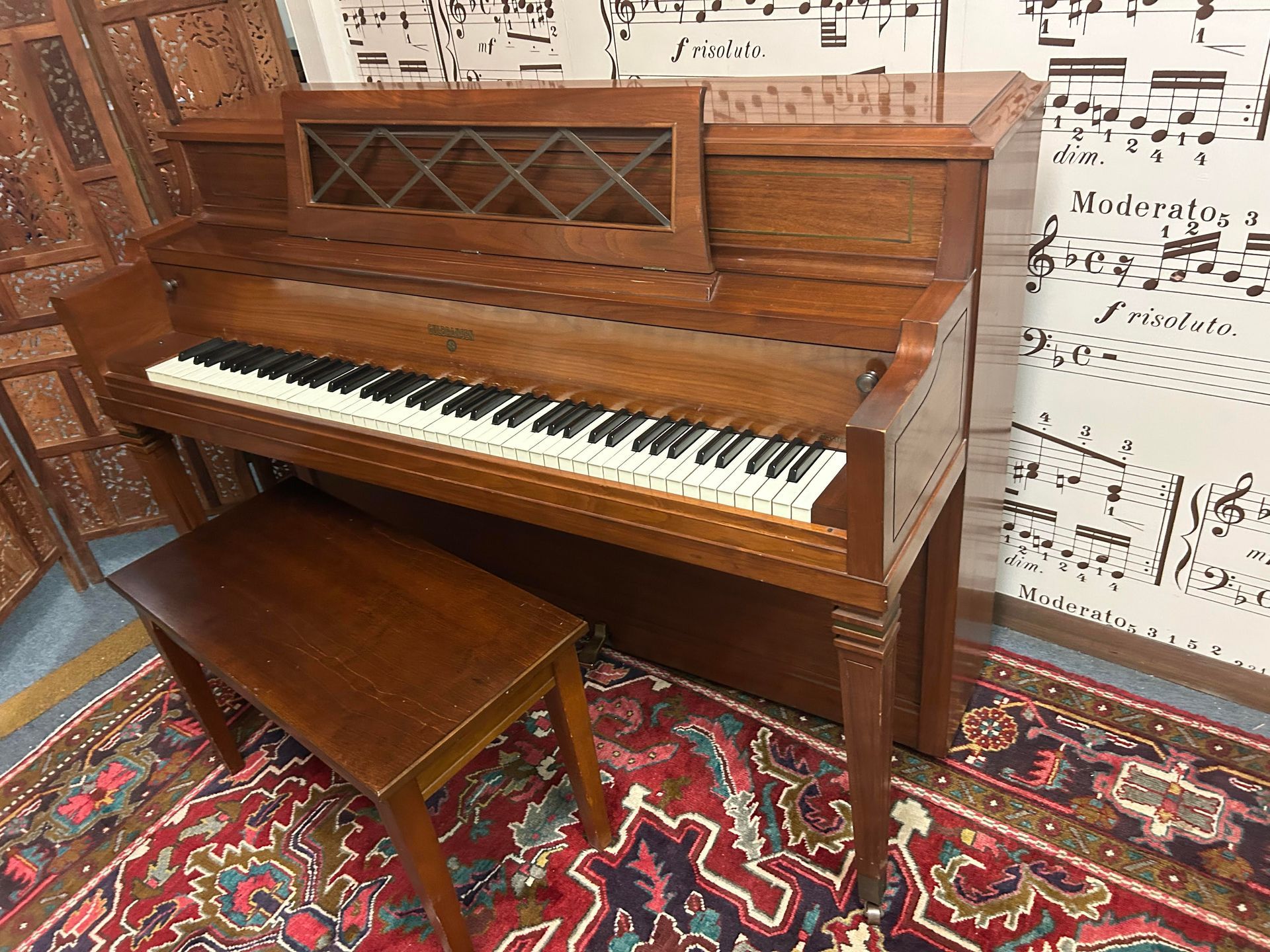 A piano with a bench next to it in a room with music notes on the wall.