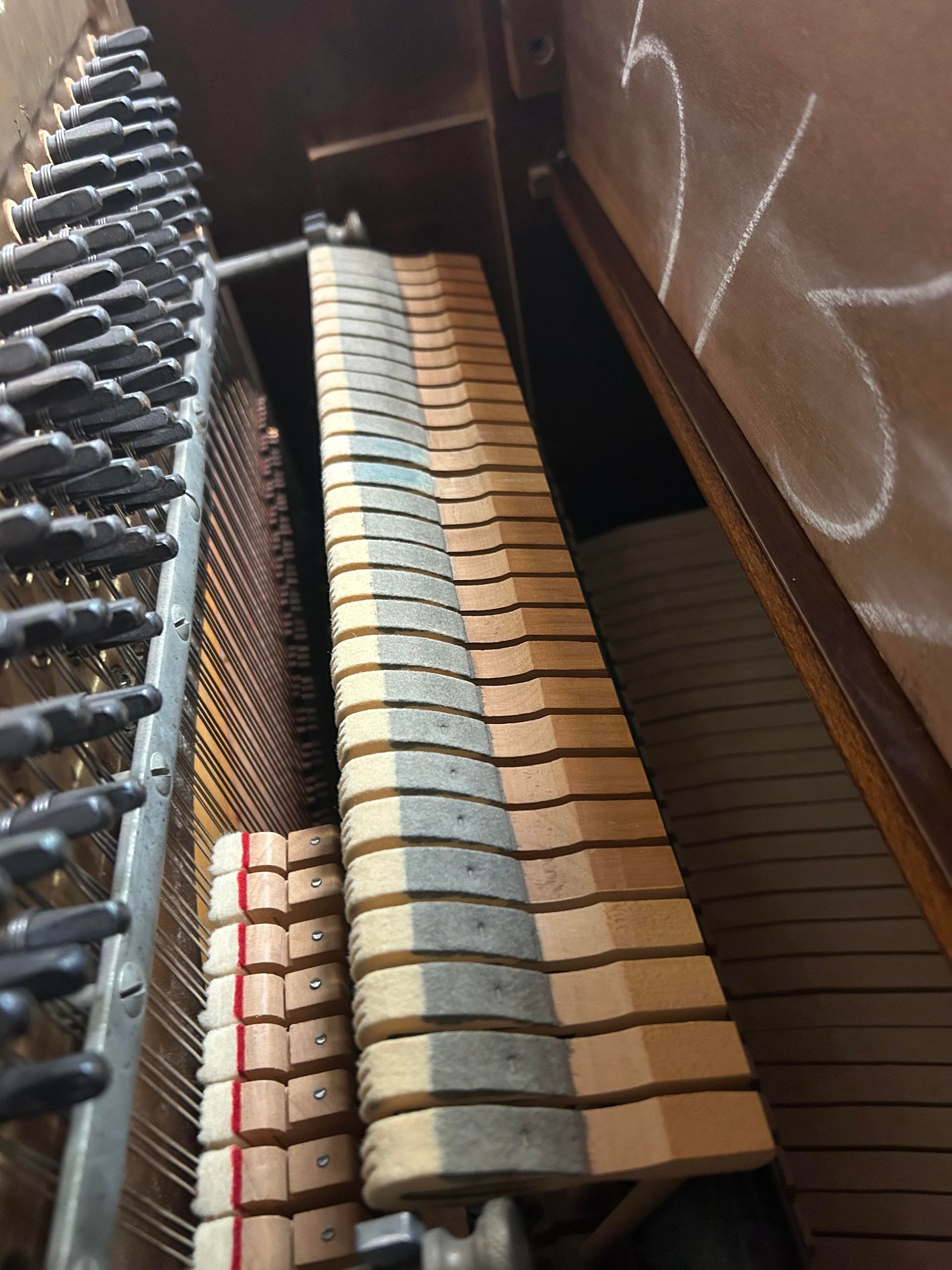 A close up of the inside of a piano showing the keys