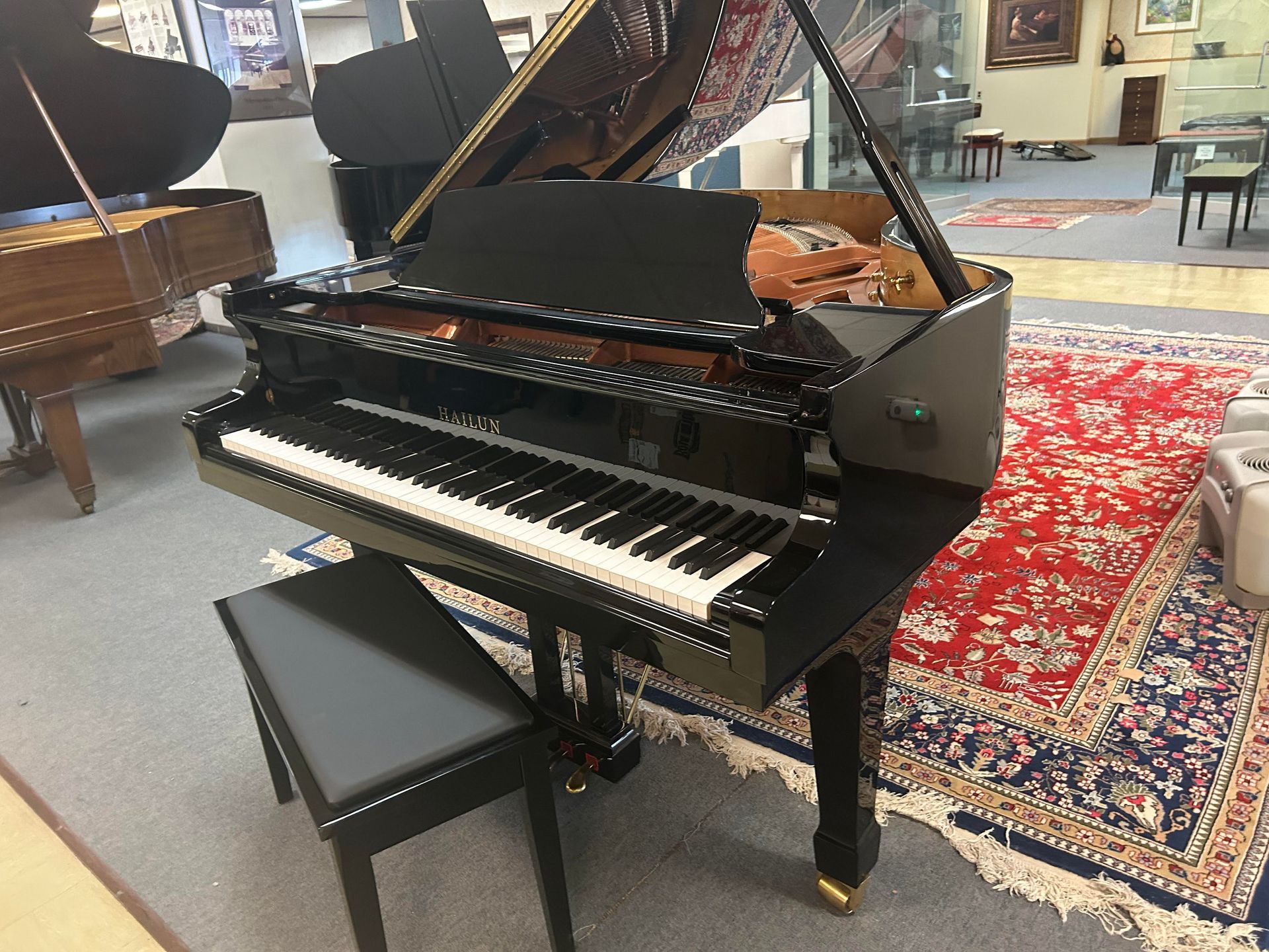 A black grand piano is sitting in a room with other pianos