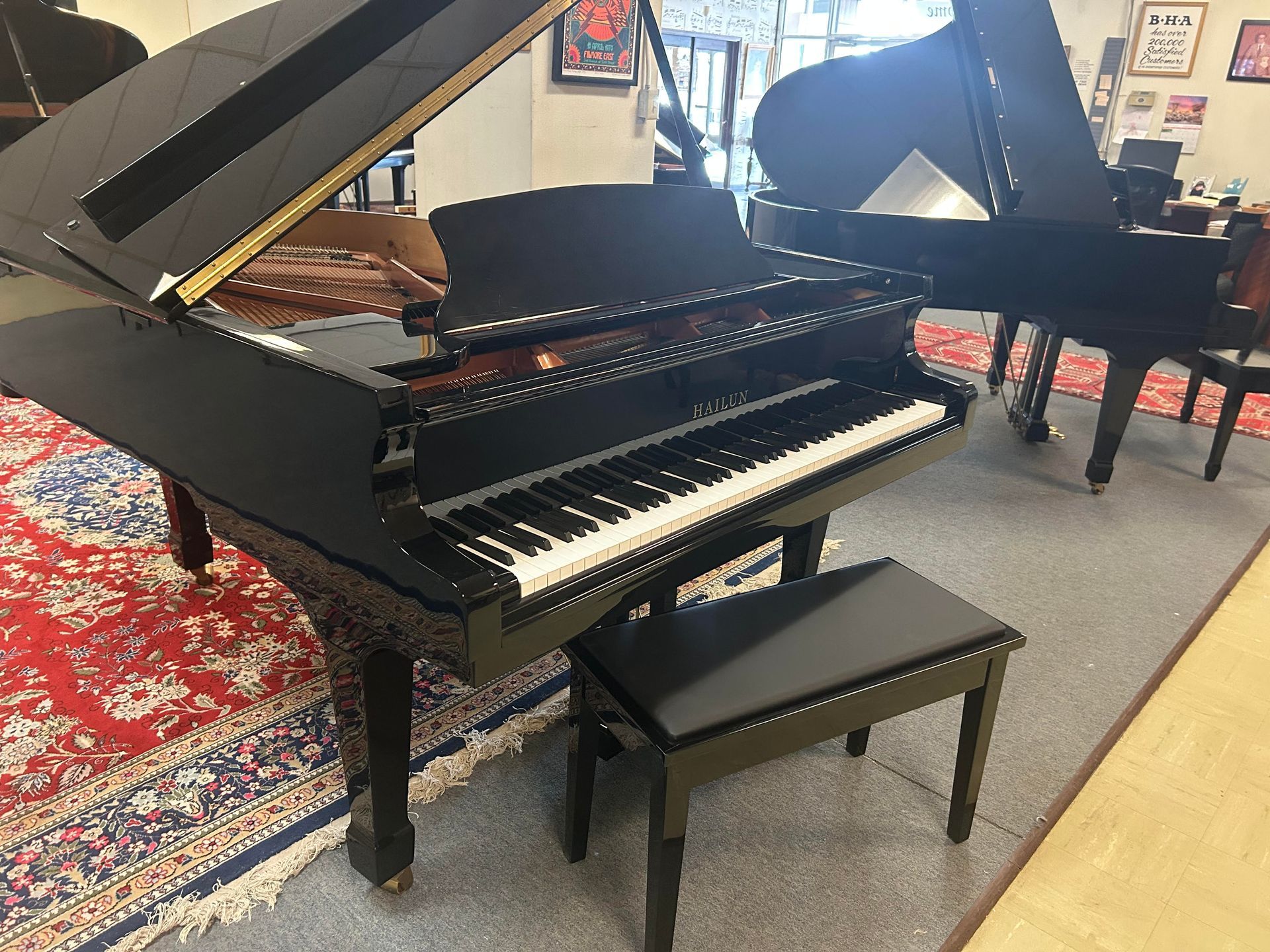 A black grand piano is sitting in a room with other pianos.
